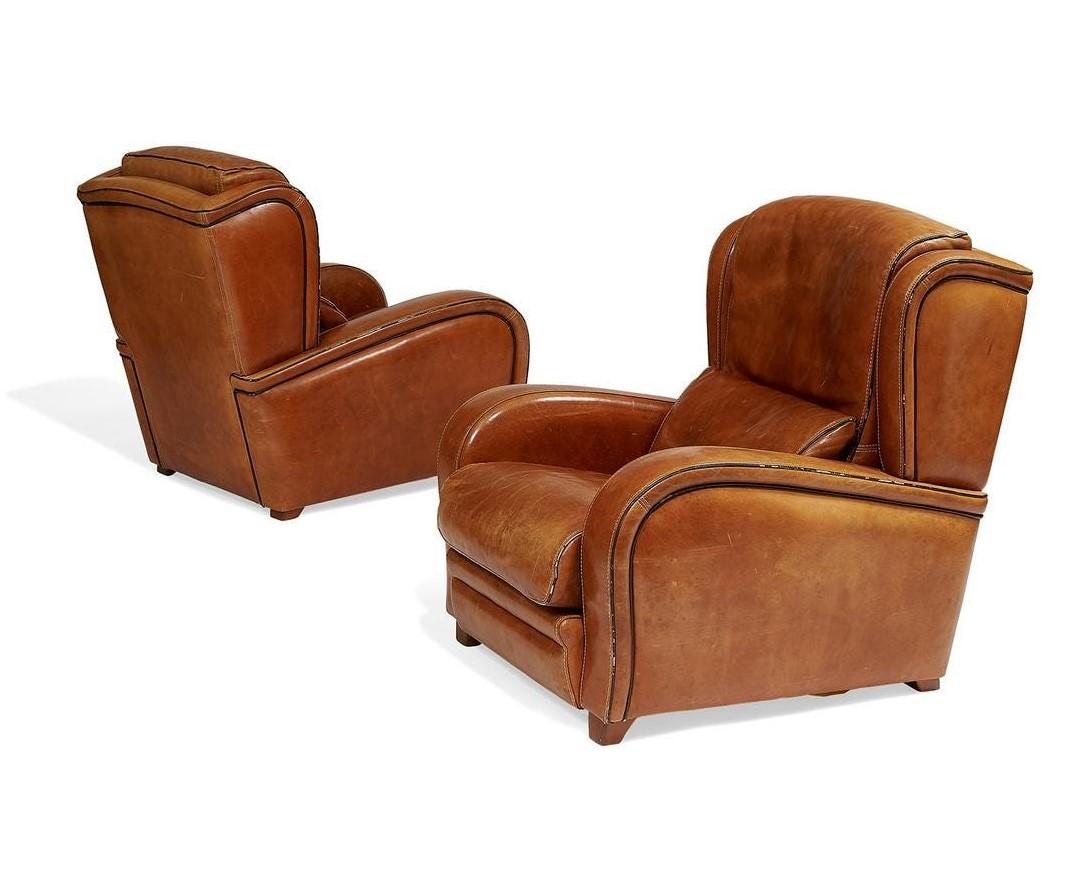 Pair of 1950s French leather lounge chairs. The chairs are cognac leather with wood legs.