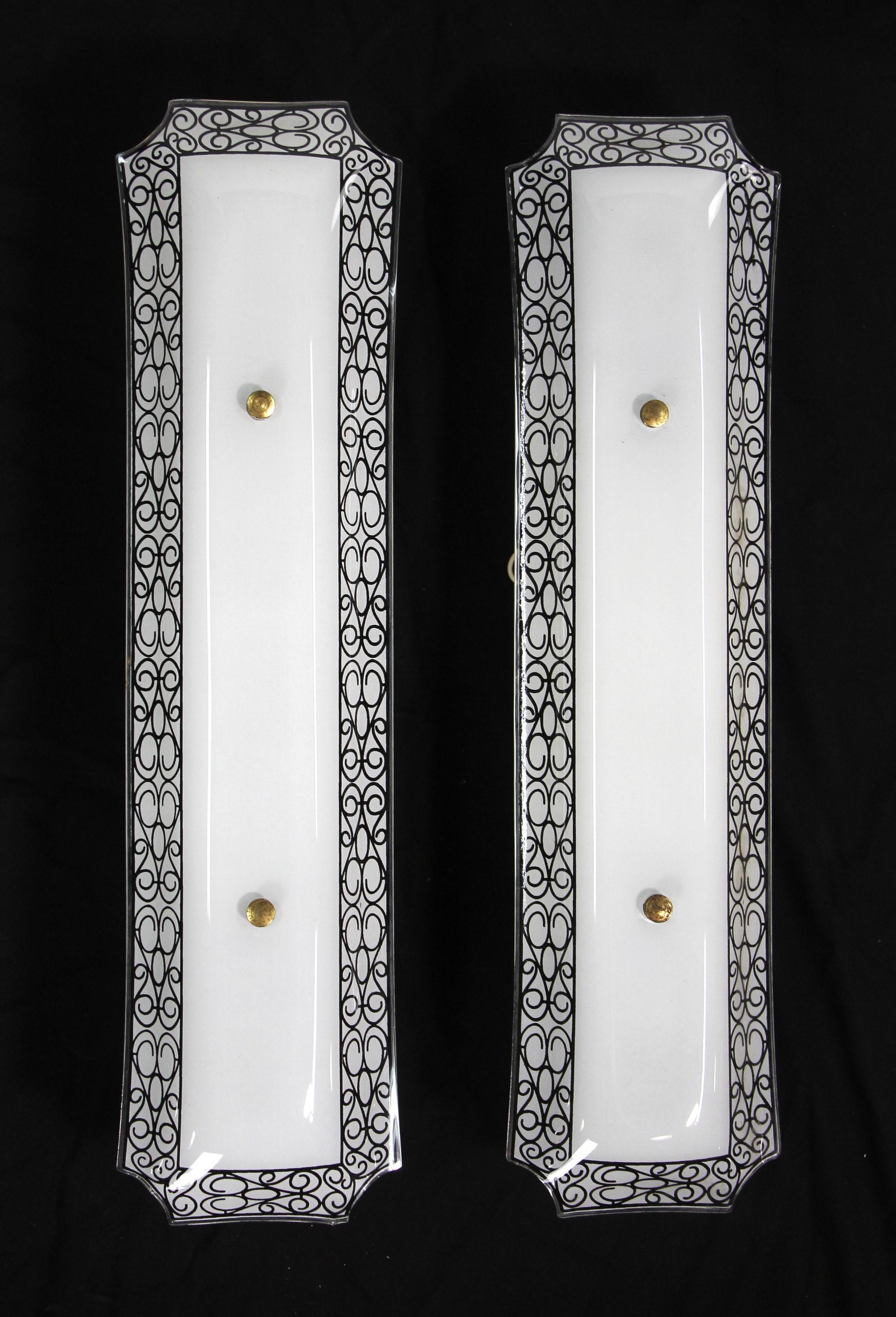 1950s French style bathroom wall sconces with long white glass surrounded by ornate black swirls.  They are mounted on a white enameled mounting plate.  Each of the sconces takes two bulbs.  Made in the U.S.  The price includes restoration. Priced