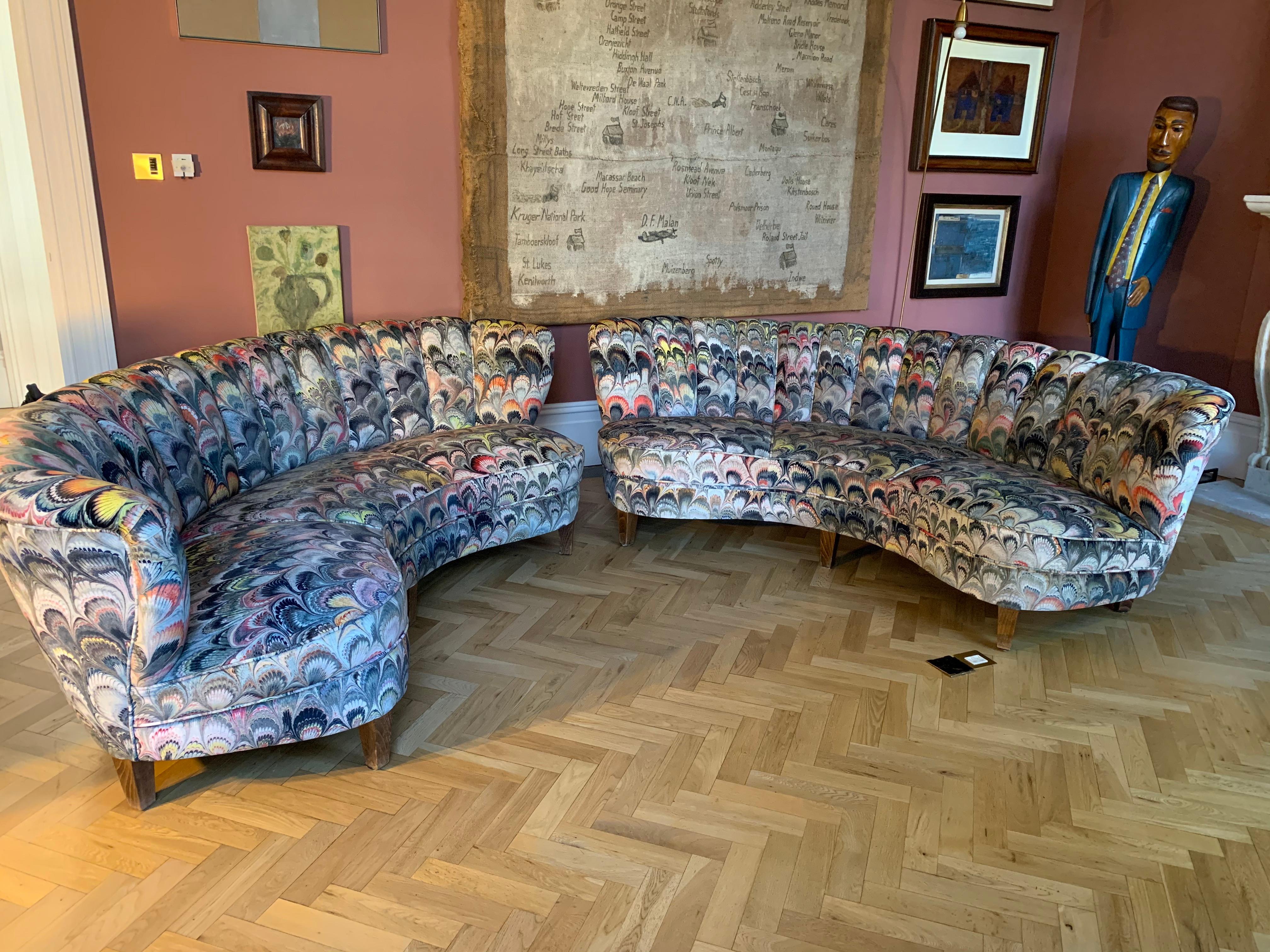 A stunning and striking pair of reupholstered 1950s German scallop backed curved lounge sofas. Each sofa has been recently recovered in Beata Heuman's sumptuous velvet marbleized fabric which has an infinite number of colors in a repeating feather