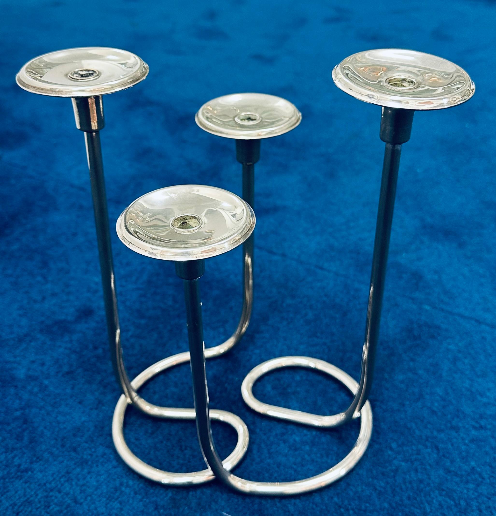 An unusual and playful pair of intertwining 1950s German silver-plate candleholders in the style of designer Wilhelm Wagenfeld.  A wonderfully simple modernist and minimalist design with each corresponding side interlocking to form a 4 stem holder