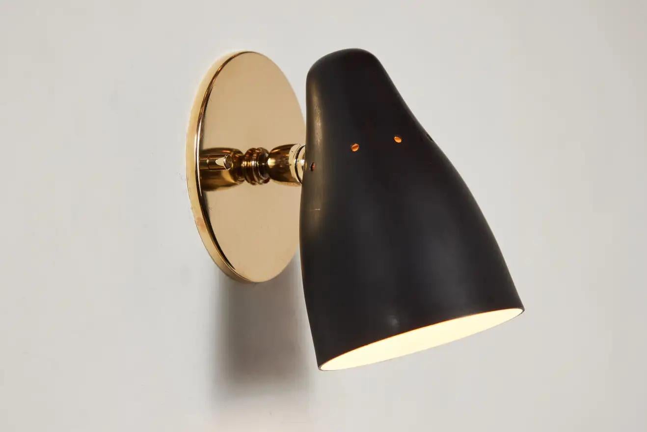 Pair of 1950s Gino Sarfatti articulating sconces for Arteluce. Executed in black painted perforated metal and brass. Ball jointed arm connection to shade allows for flexible shade adjustments and multiple configurations. The simplicity of Sarfatti's