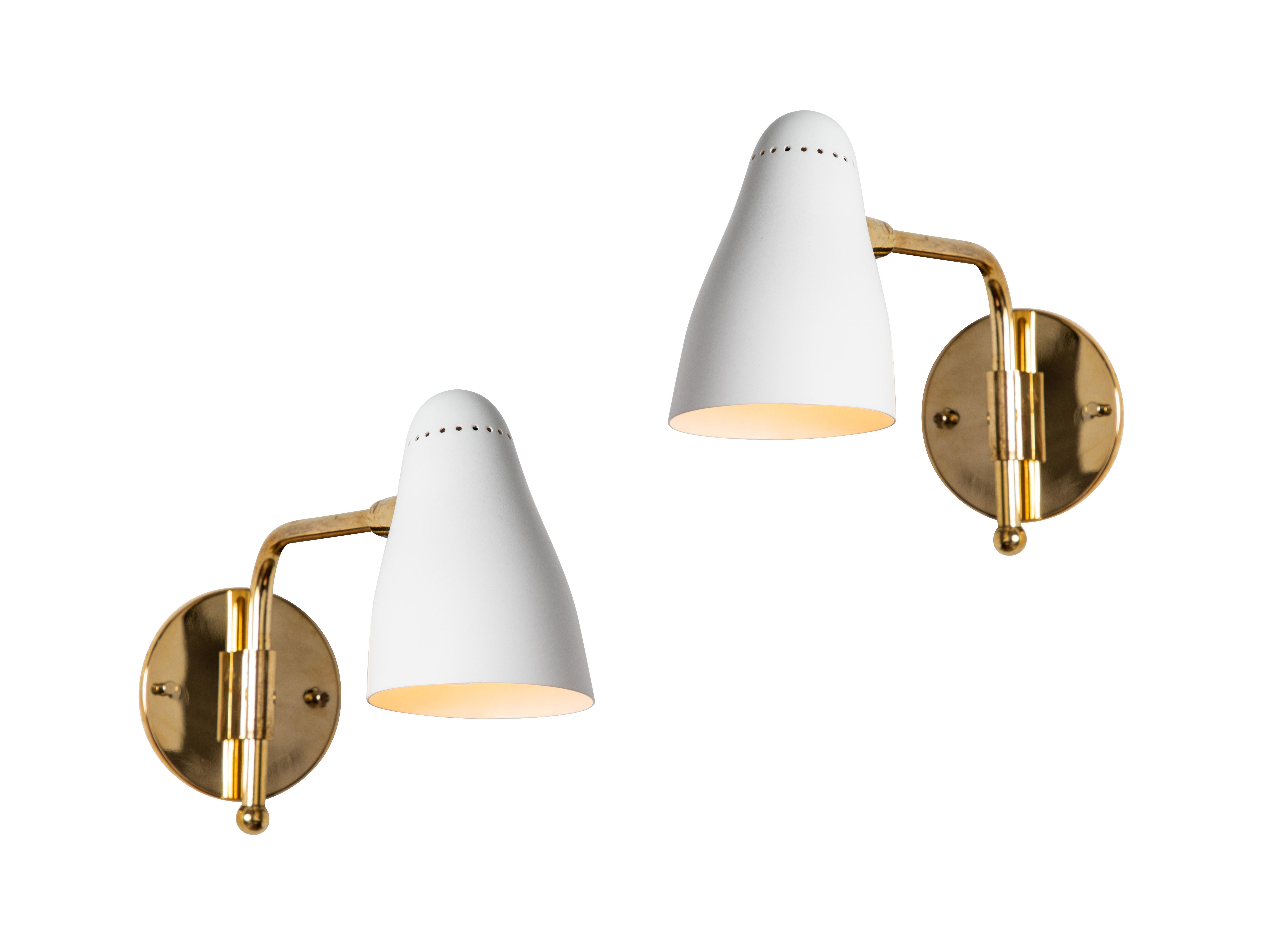 Pair of 1950s Giuseppe Ostuni articulating sconces for O-Luce. Executed in brass and white painted aluminum with perforated shade. Shade pivots up/down on a ball joint and arm rotates freely left/right. A very rare and exceptional example of