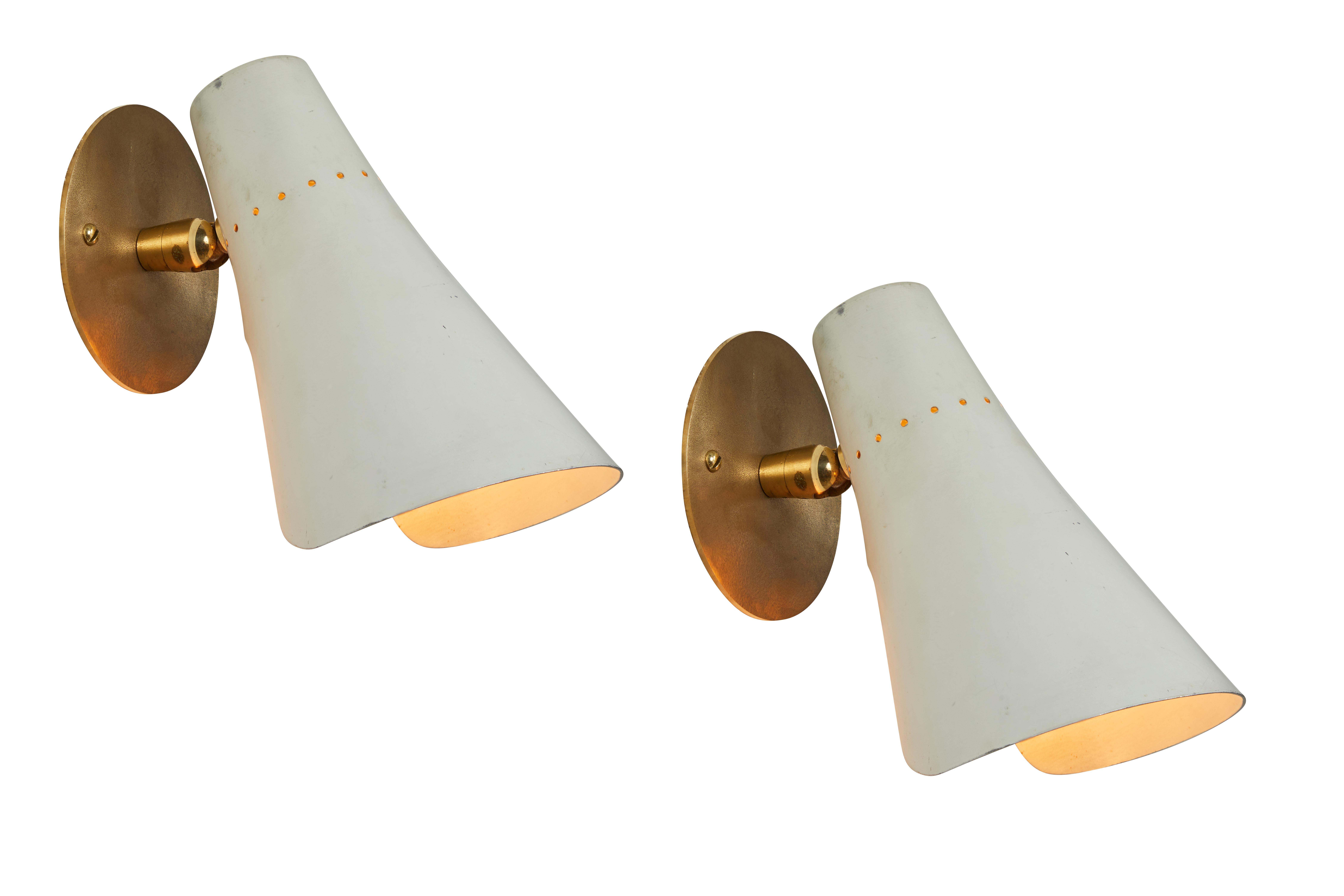 Pair of 1950s Giuseppe Ostuni articulating sconces for O-Luce. Executed in brass and white painted aluminum with perforated shade. Sconces pivot up/down and rotate left/right. Reminiscent of the midcentury Italian designs of Gino Sarfatti for