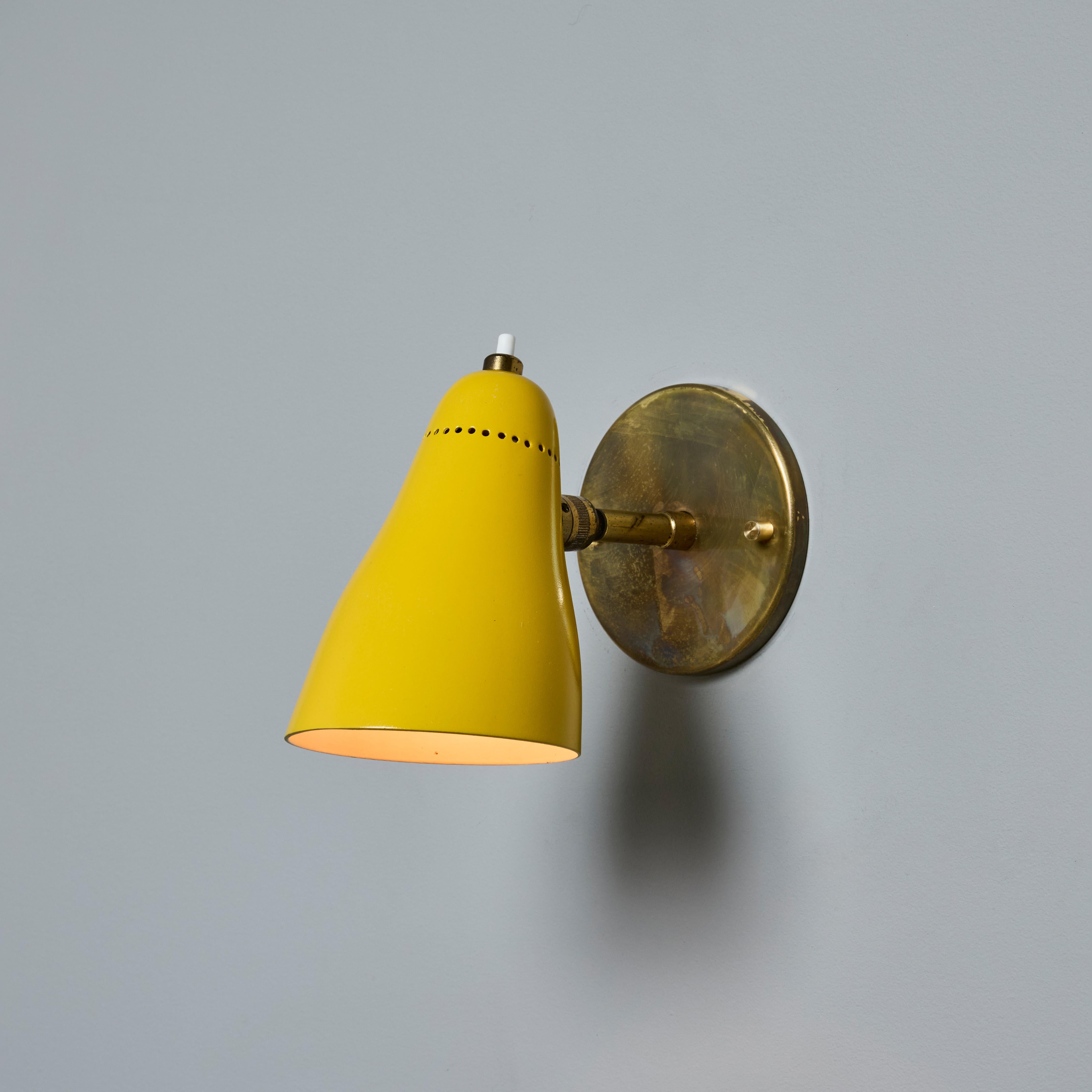 Coppia di lampade gialle snodabili Giuseppe Ostuni Model #101 degli anni '50 per O-Luce. Eseguita in ottone patinato e paralume in alluminio perforato verniciato giallo. Le applique sono orientabili verso l'alto/il basso e verso sinistra/destra. Un