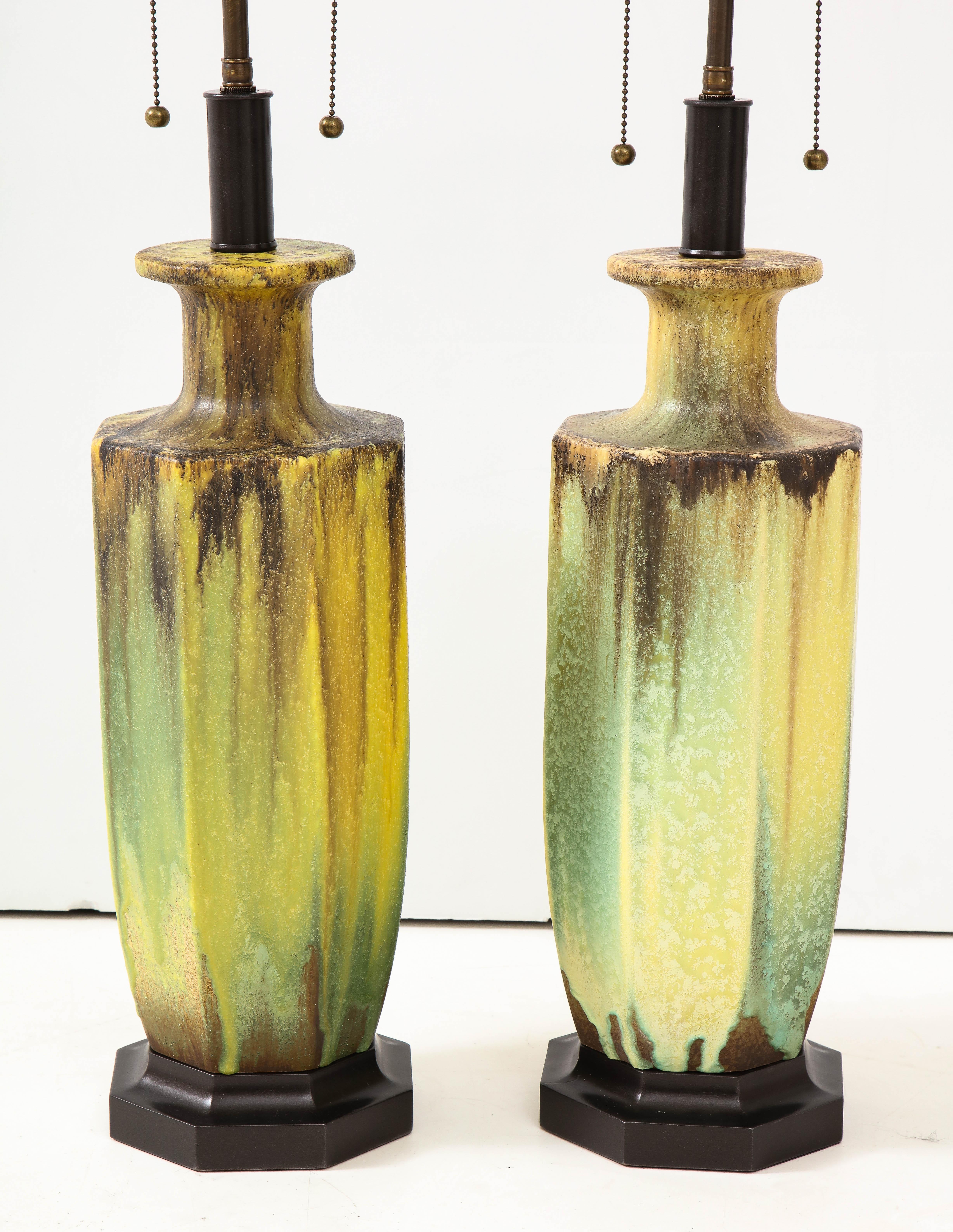Pair of 1950s glazed ceramic lamps in the Arts & Crafts style.
The lamps have a beautiful glazed finish and they are mounted on bronze colored wooden bases.
They have been newly rewired with bronze finished double clusters that take standard size