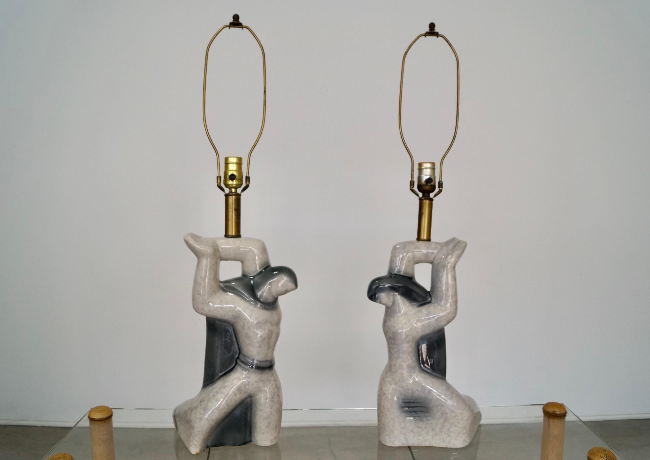 Pair of vintage 1950’s Mid-century Modern table lamps for sale. Manufactured by Heifetz Lighting, and in amazing condition with no chips or cracks. They’re a male and female figures in ceramic, and are a beautiful gray tone. They have darker gray