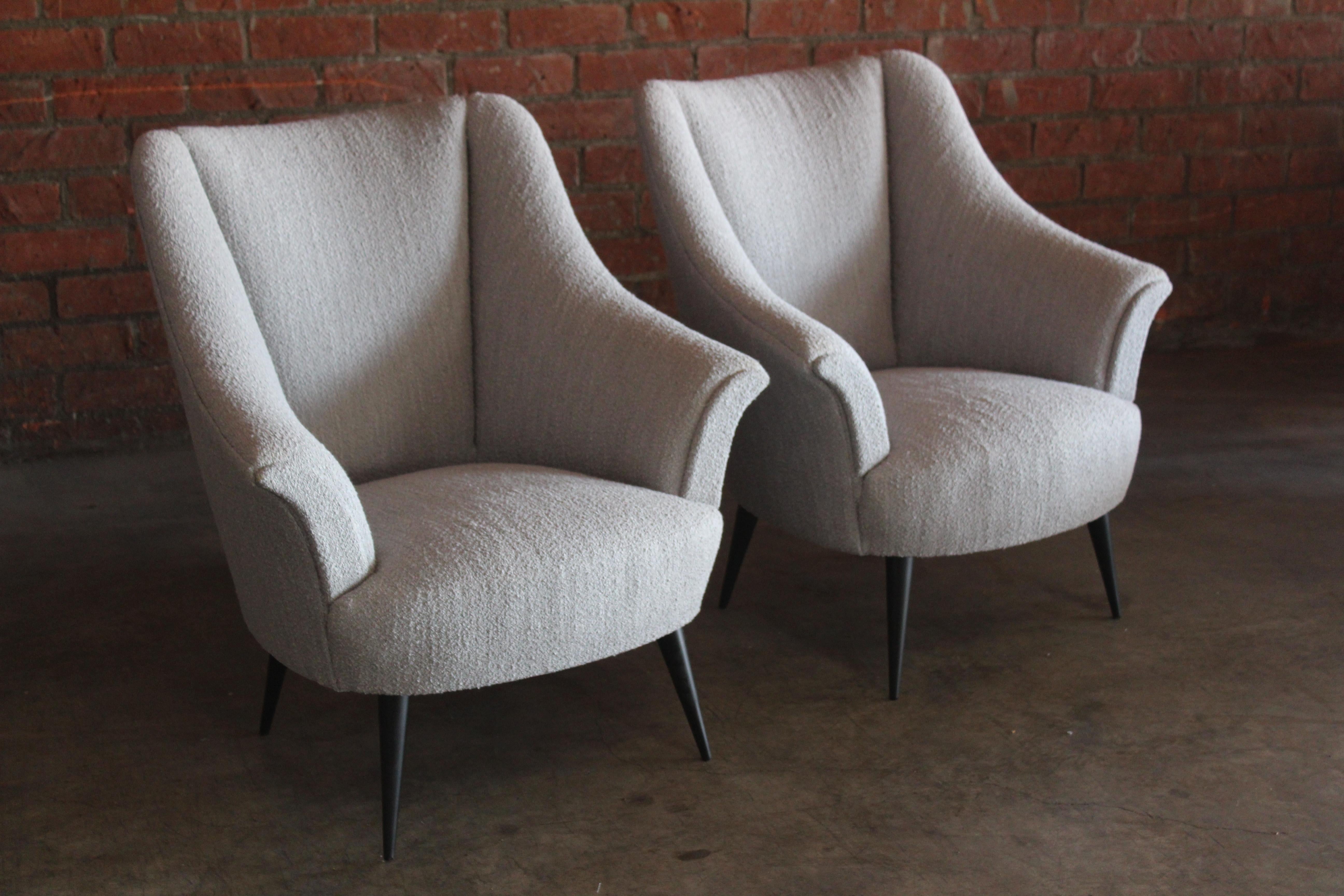 Pair of 1950s Italian armchairs completely restored and reupholstered in a light grey performance bouclé. The walnut legs have been refinished satin black. Overall the pair are in excellent condition. Sold as a pair.