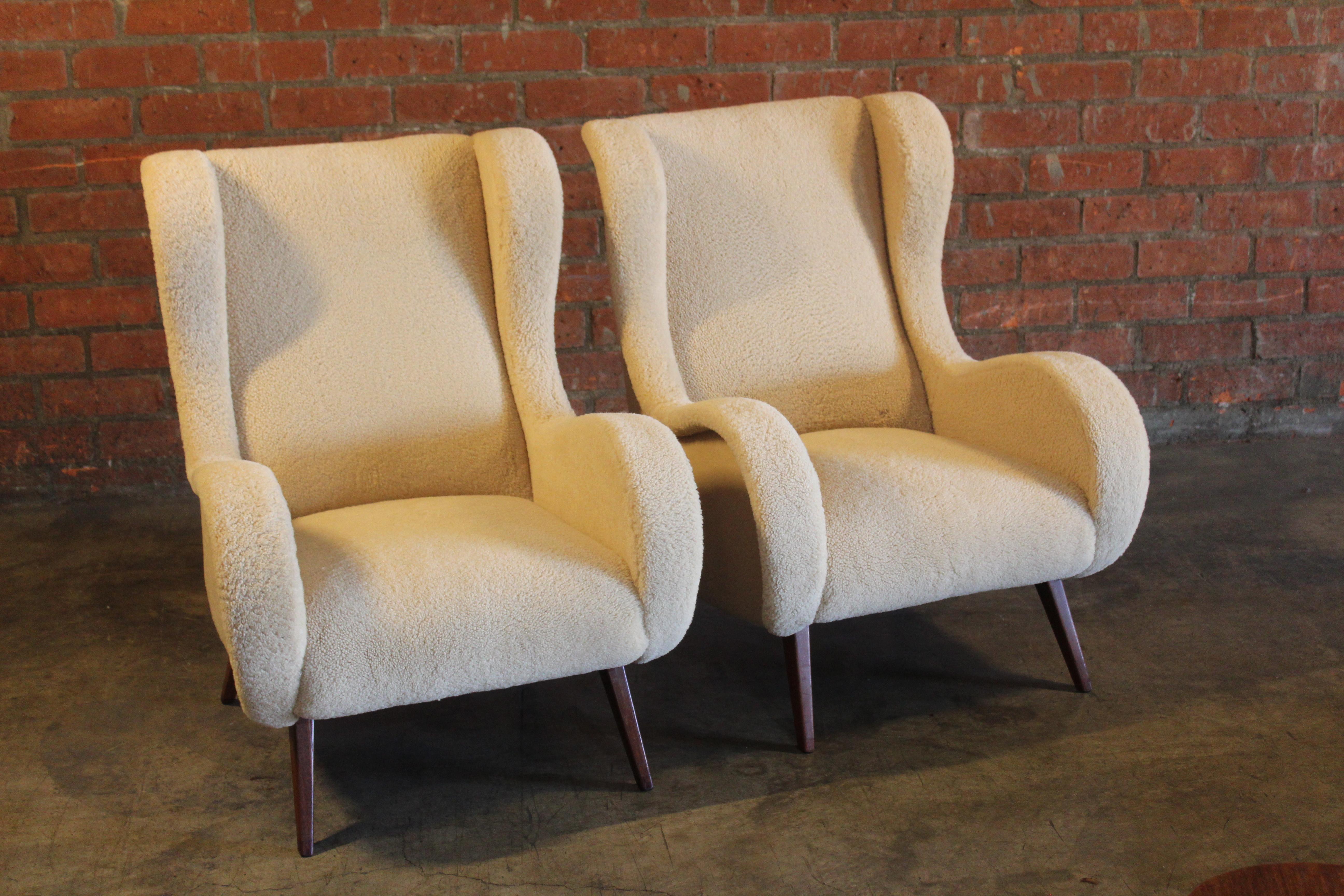 Pair of vintage 1950s armchairs attributed to Marco Zanuso. Newly upholstered in sheepskin. They feature walnut tapered legs. In overall excellent condition. The walnut legs show minor wear and were touched up.