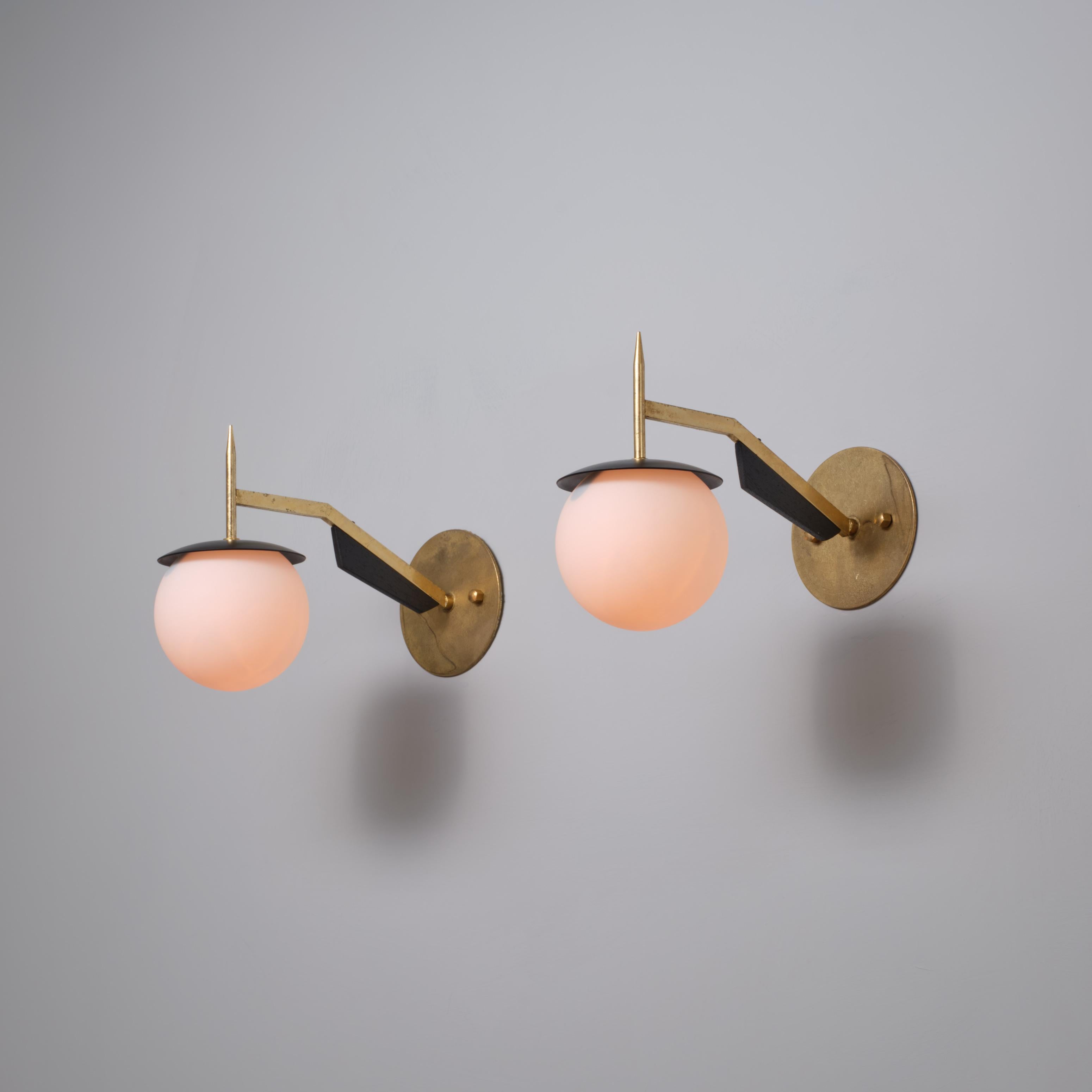 Paire d'appliques murales italiennes des années 1950, chacune dotée d'un bras en laiton à géométrie angulaire et d'un fleuron vertical, s'étendant à partir d'une plaque murale circulaire (12 cm de diamètre) pour soutenir un diffuseur sphérique en