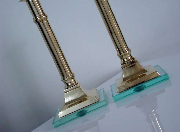 Beautiful pair of Italian Mid-Century Modern brass pedestal candleholders with glass bases in the manner of Fontana Arte.