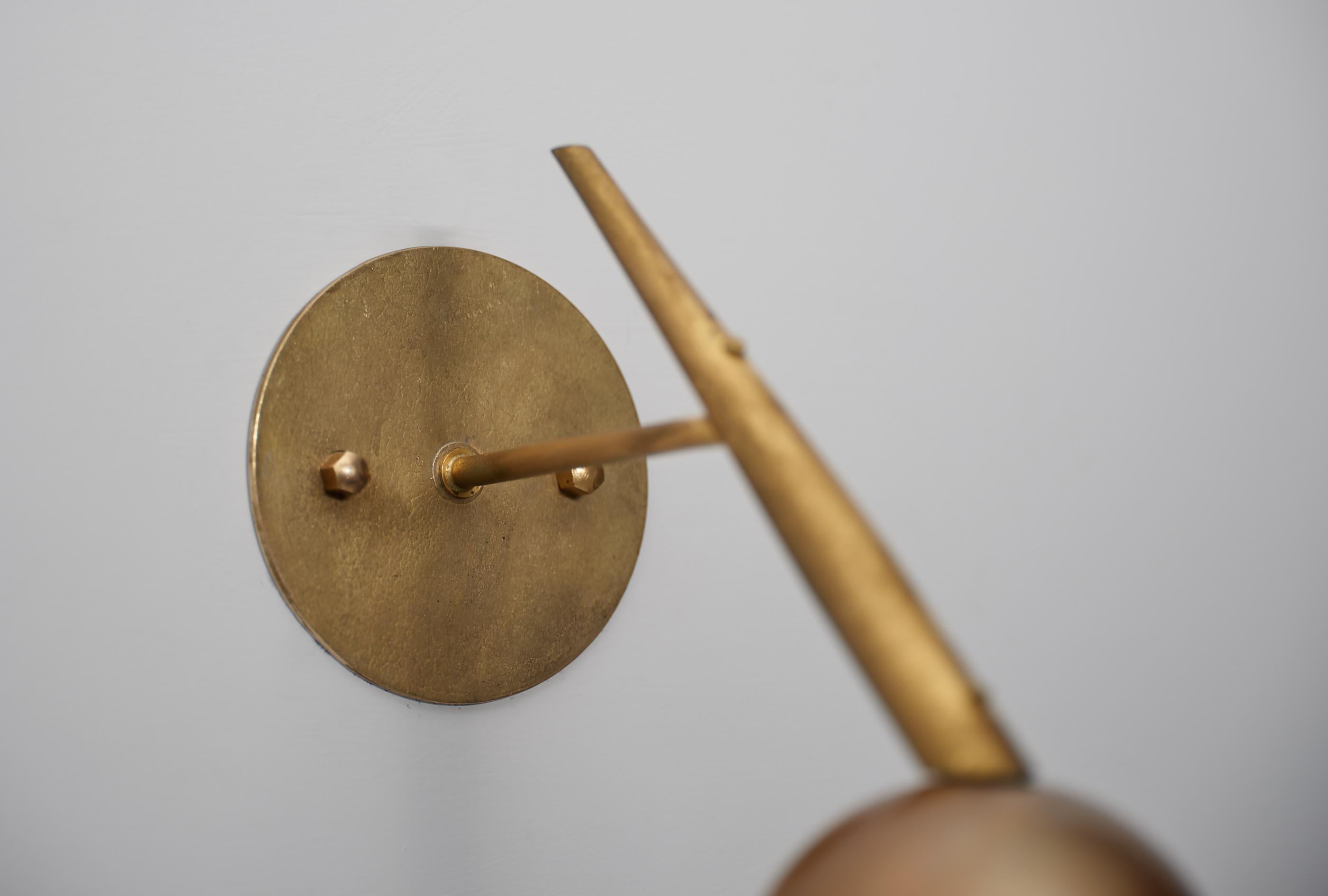 Questa coppia di appliques italiane degli anni '50 combina una raffinata silhouette modernista con ricche superfici in ottone e vetri delicatamente luminosi. Ogni applique è costruita attorno a una piastra posteriore circolare in ottone (diametro di