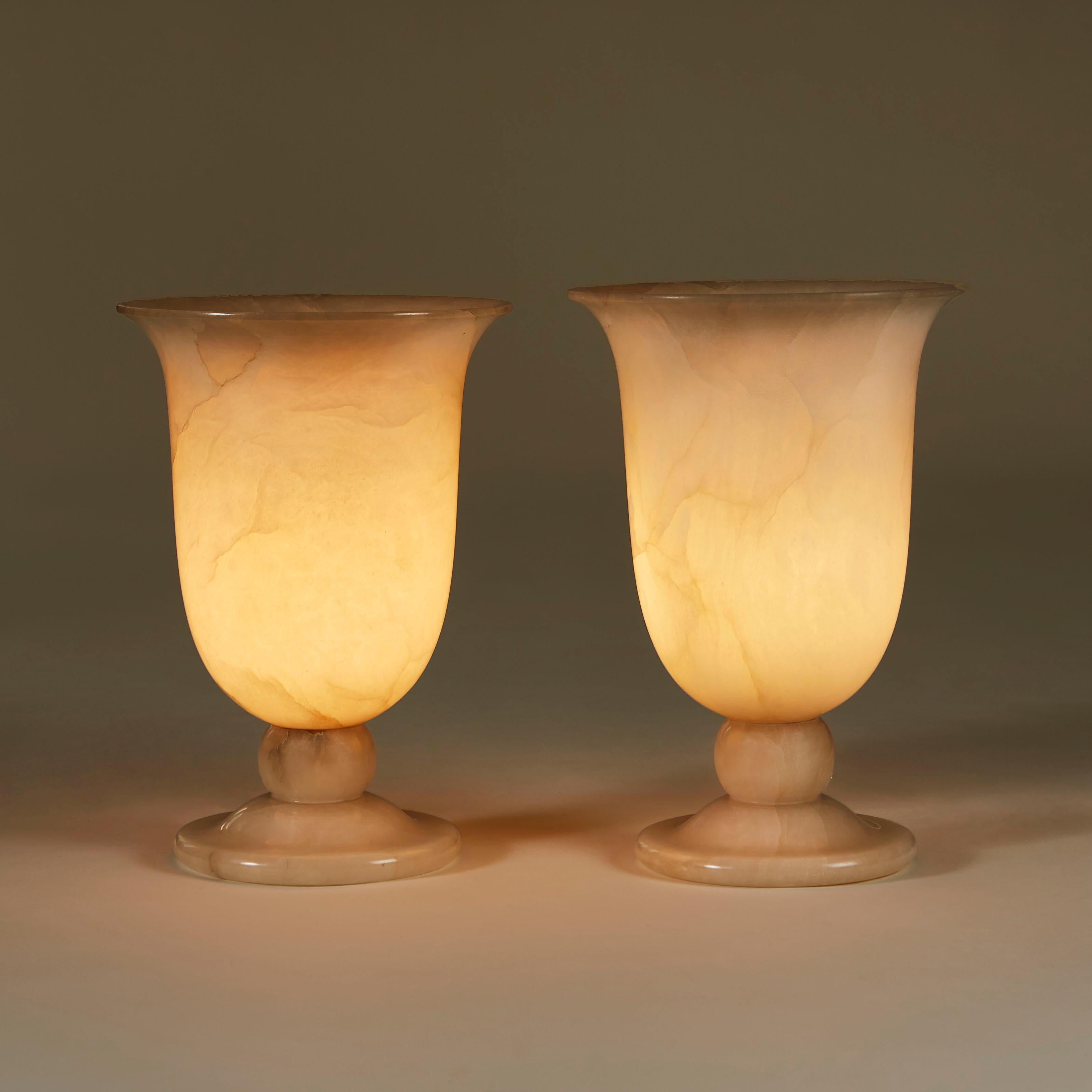 Substantial pair of 1950s Italian alabaster urn lamps. The elegantly carved base has ball detailing and open curved vase shaped top. The patina is enhanced by subtle markings in the alabaster and results in a flattering warm glow.