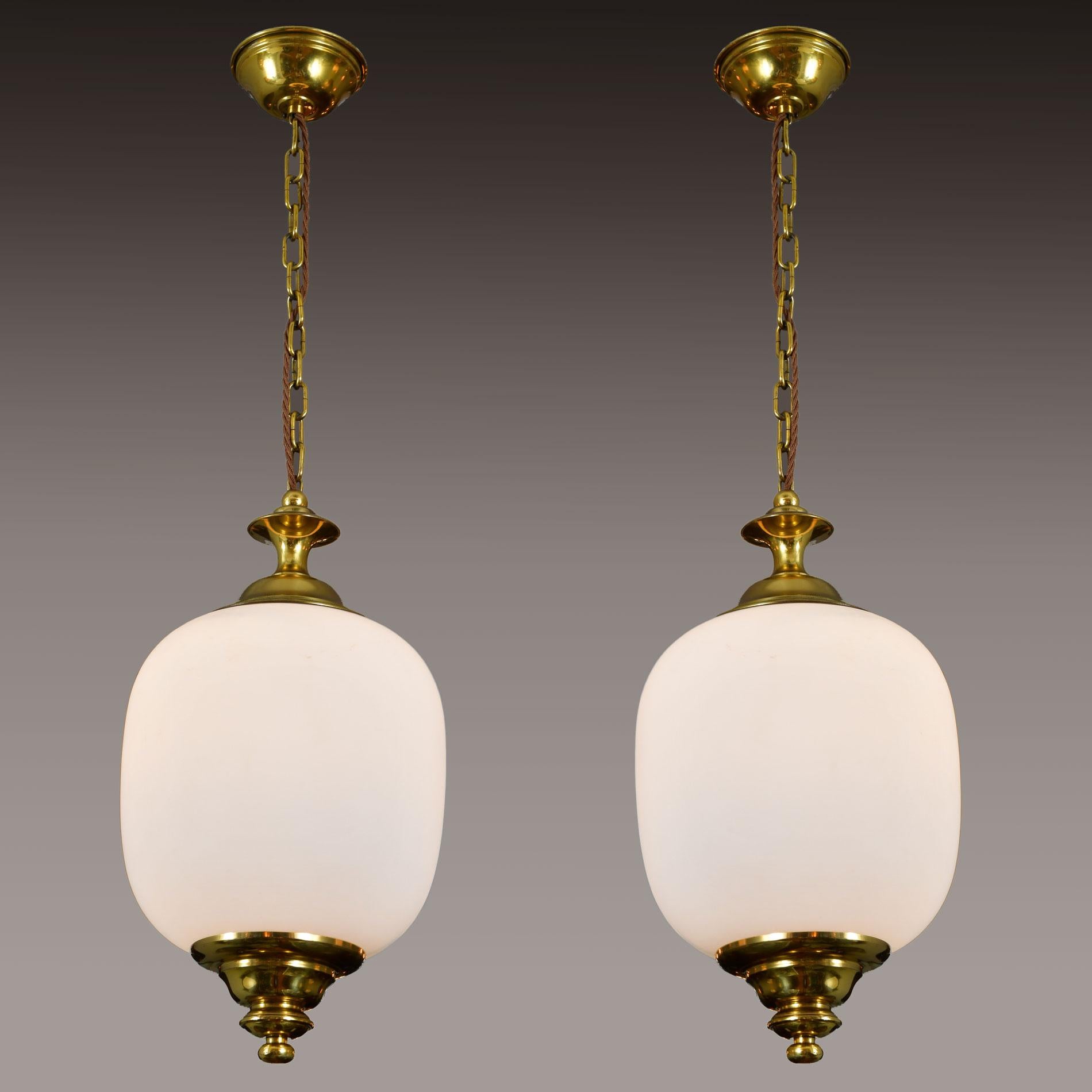 Midcentury Italian opaque white glass pendants with decorative tiered brass detail on either end of glass dome.