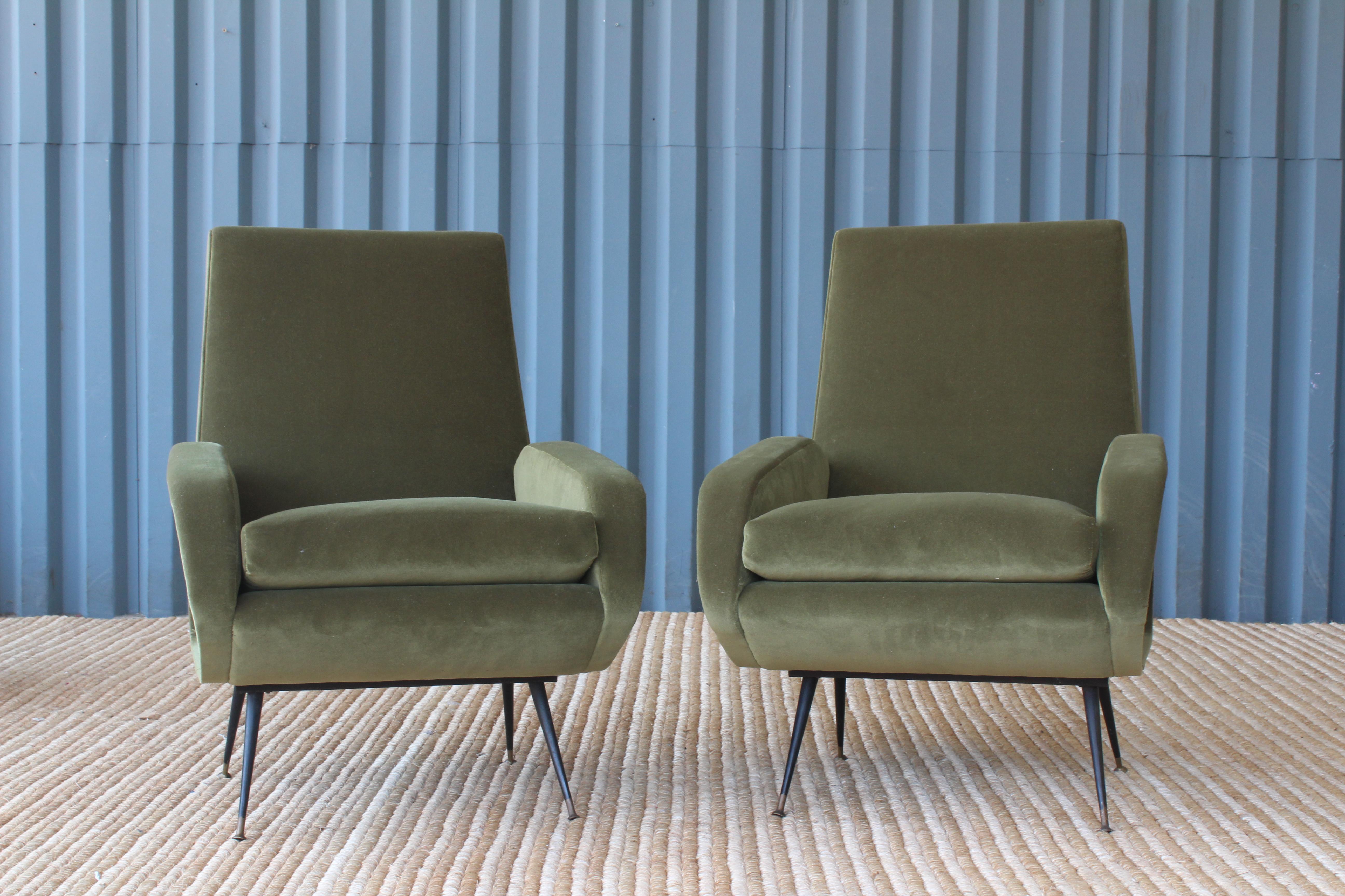 Pair of 1950s Italian modern armchairs. The pair feature new upholstery in a green performance velvet and sit on metal bases with brass capped feet.