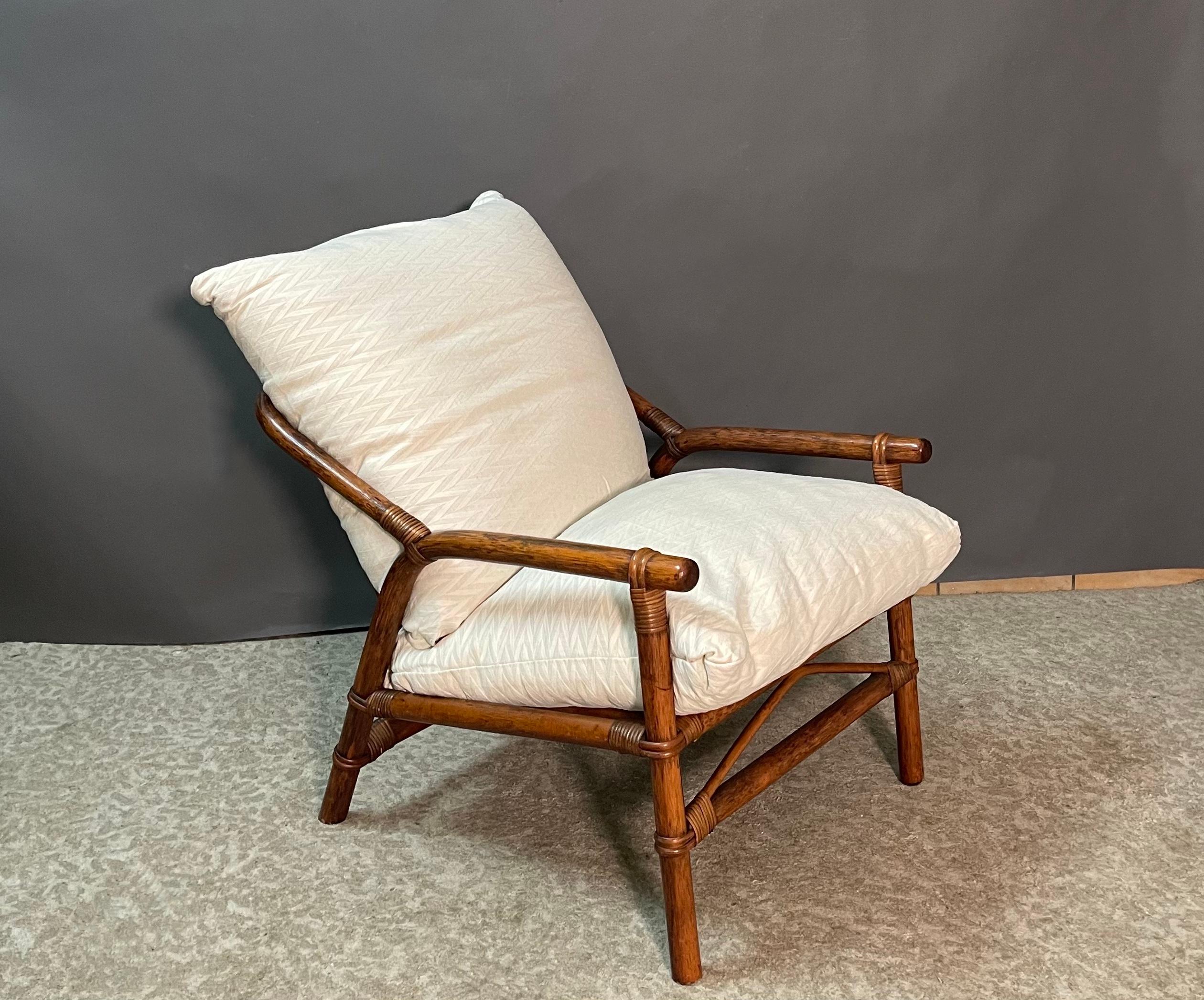 Beautiful pair of Italian colonial-style faux bamboo structure woven with rattan armchairs.
The arm style flows sinuously into a the rounded back of the chairs. 
A very comfortable pair of lounge chairs from the 1950s.
 Great profile and very