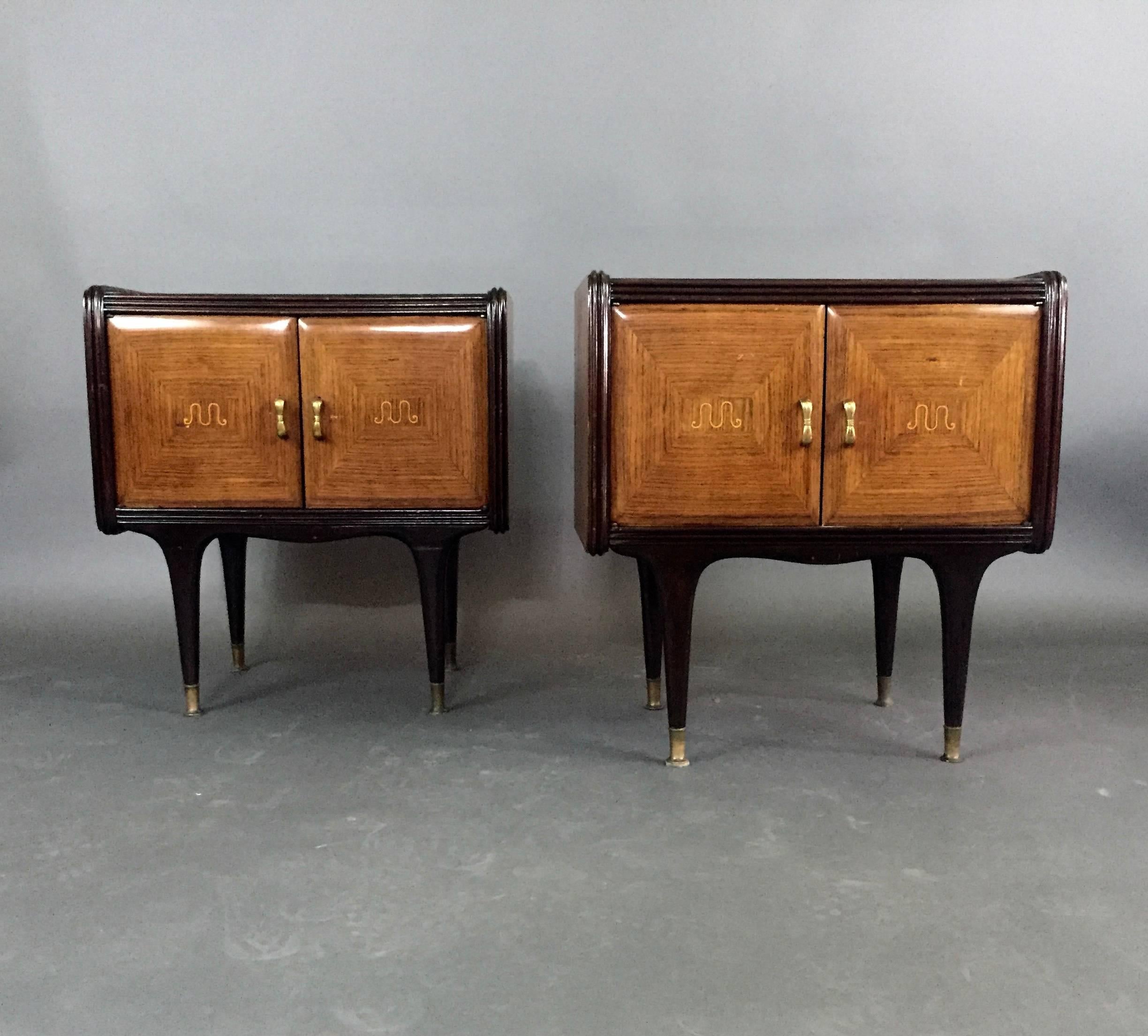 A gorgeous pair of nightstands designed with a rosewood veneer case surrounded with dark stained channelled framing. Each door panel is quartered, curved at the edges and is centred with light-stained intarsia. Four black lacquered legs are finished