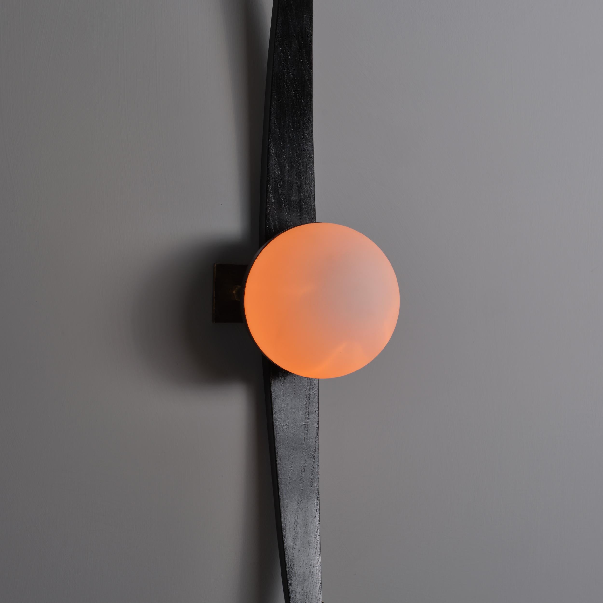 Pair of wall sconces produced in Italy during the 1950s, attributed to Stilnovo. Each sconce features a vertical curved support in black lacquered wood (newly refinished), mounted on a burnished steel structure with a central brass fixture. The