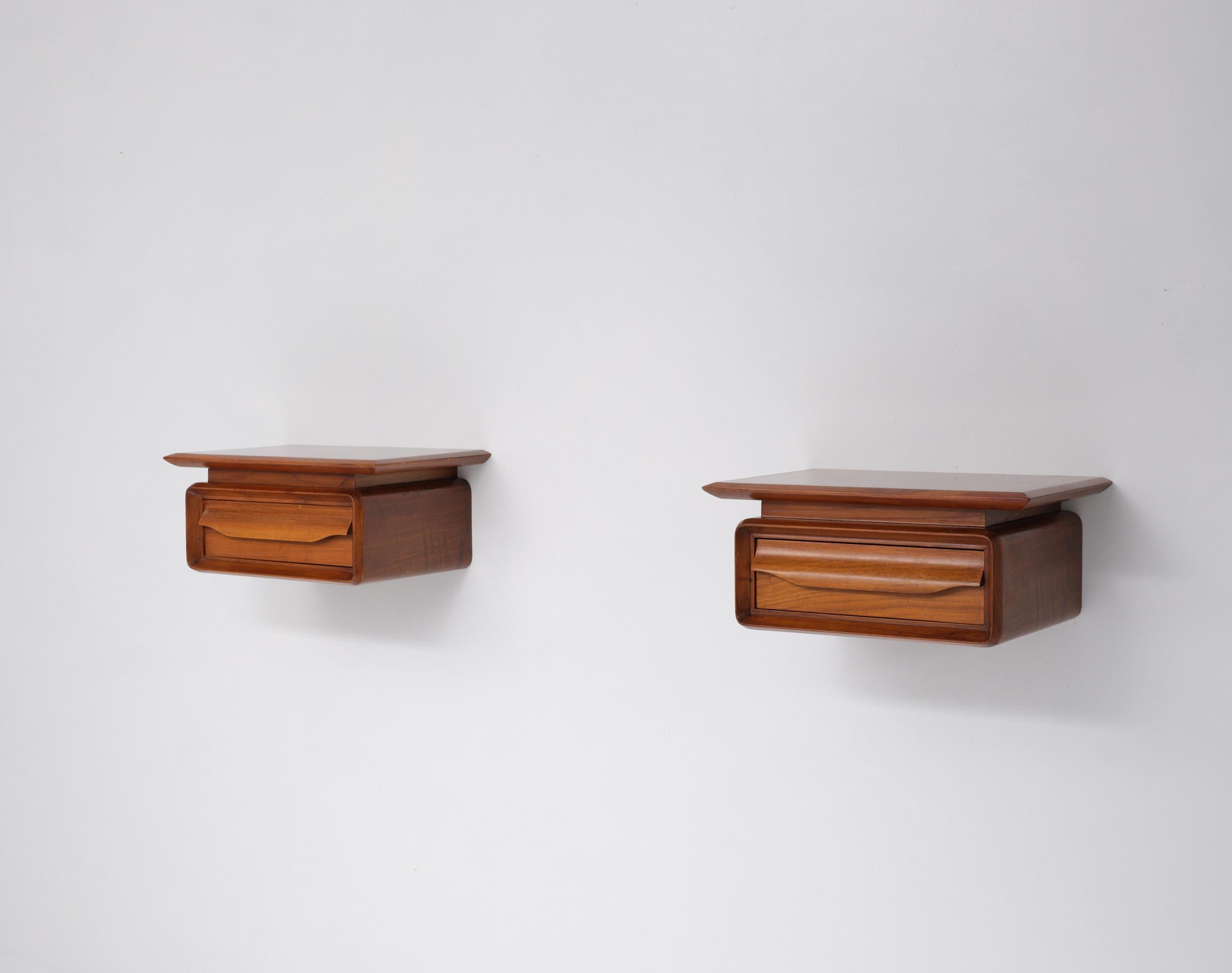 Paire de tables de nuit murales modernes des années 1950. Chaque meuble est fabriqué en bois avec une finition claire et chaude et présente un plateau en porte-à-faux, des coins doucement arrondis et un seul tiroir avec une tirette intégrée en bois
