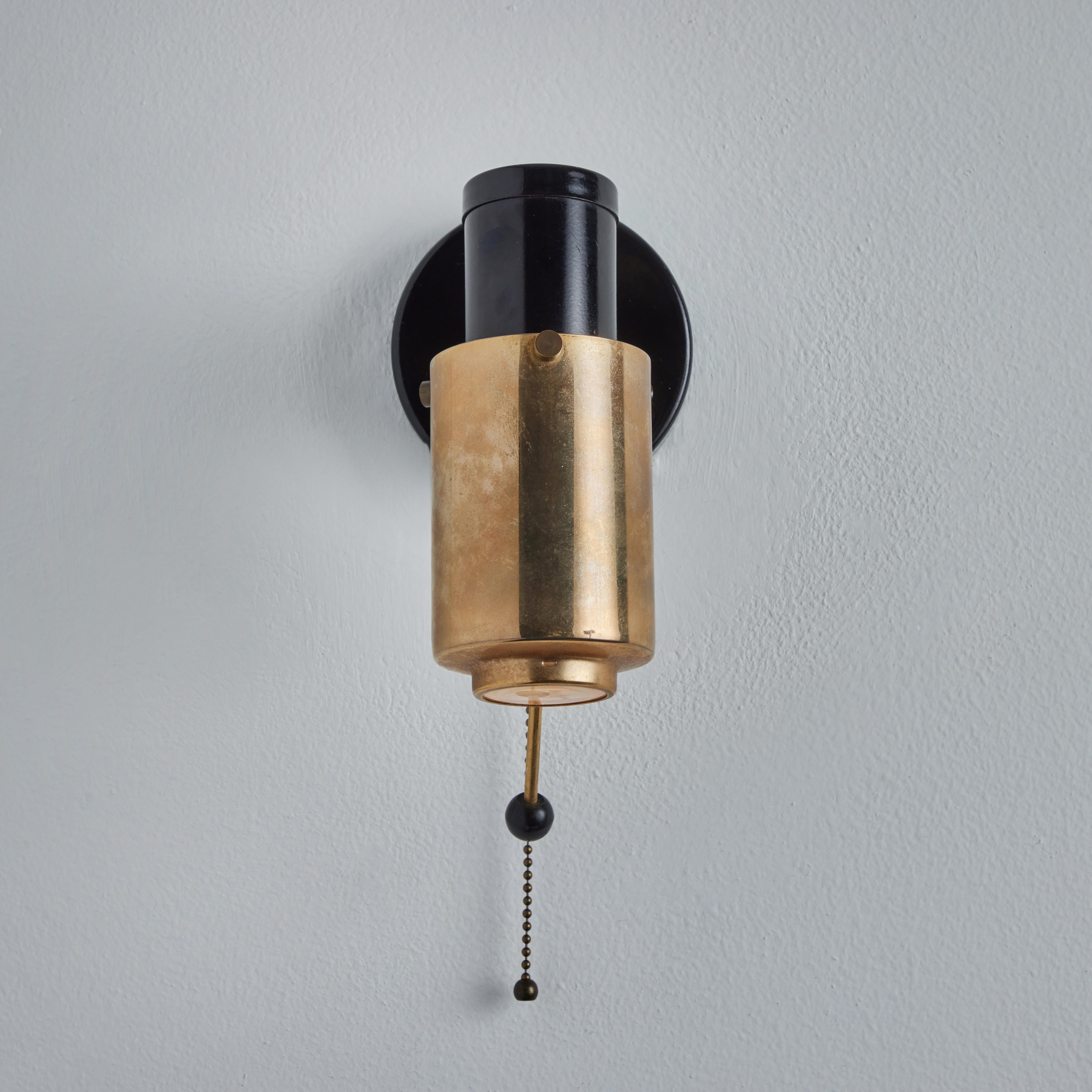 Pair of 1950s Jacques Biny black and brass 'Zodiac' wall lights for Lita. Executed in black painted metal, glass and brass for Lita, France. Retain original on/off pulls with cord. Professionally rewired for US electrical.

Price is for the