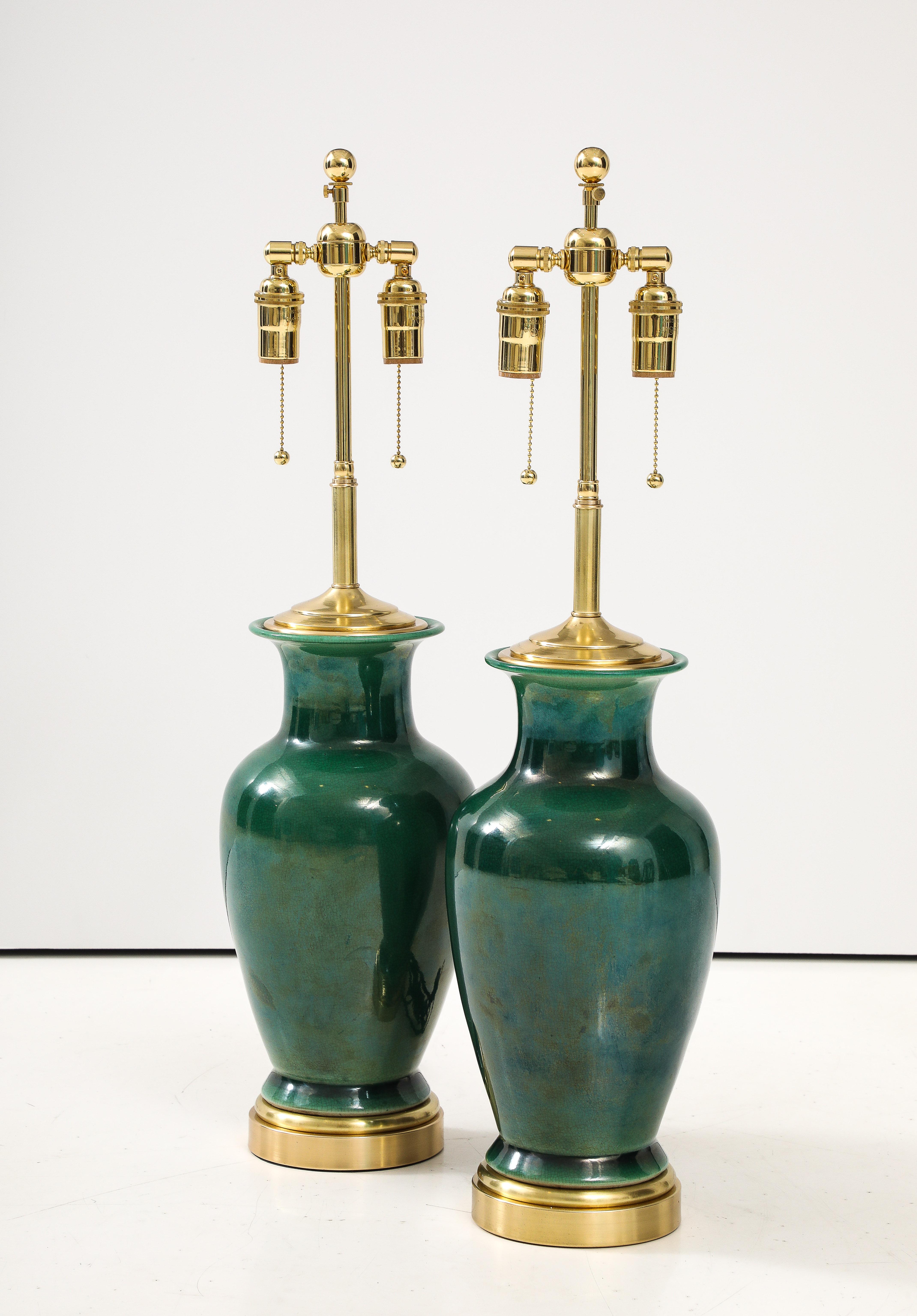 Magnifique paire de lampes japonaises en céramique en forme d'urne avec une finition de glaçure craquelée verte.
Les lampes ont été refaites à neuf avec des grappes doubles réglables en laiton poli et des lampes à incandescence. 
Corde de soie et de