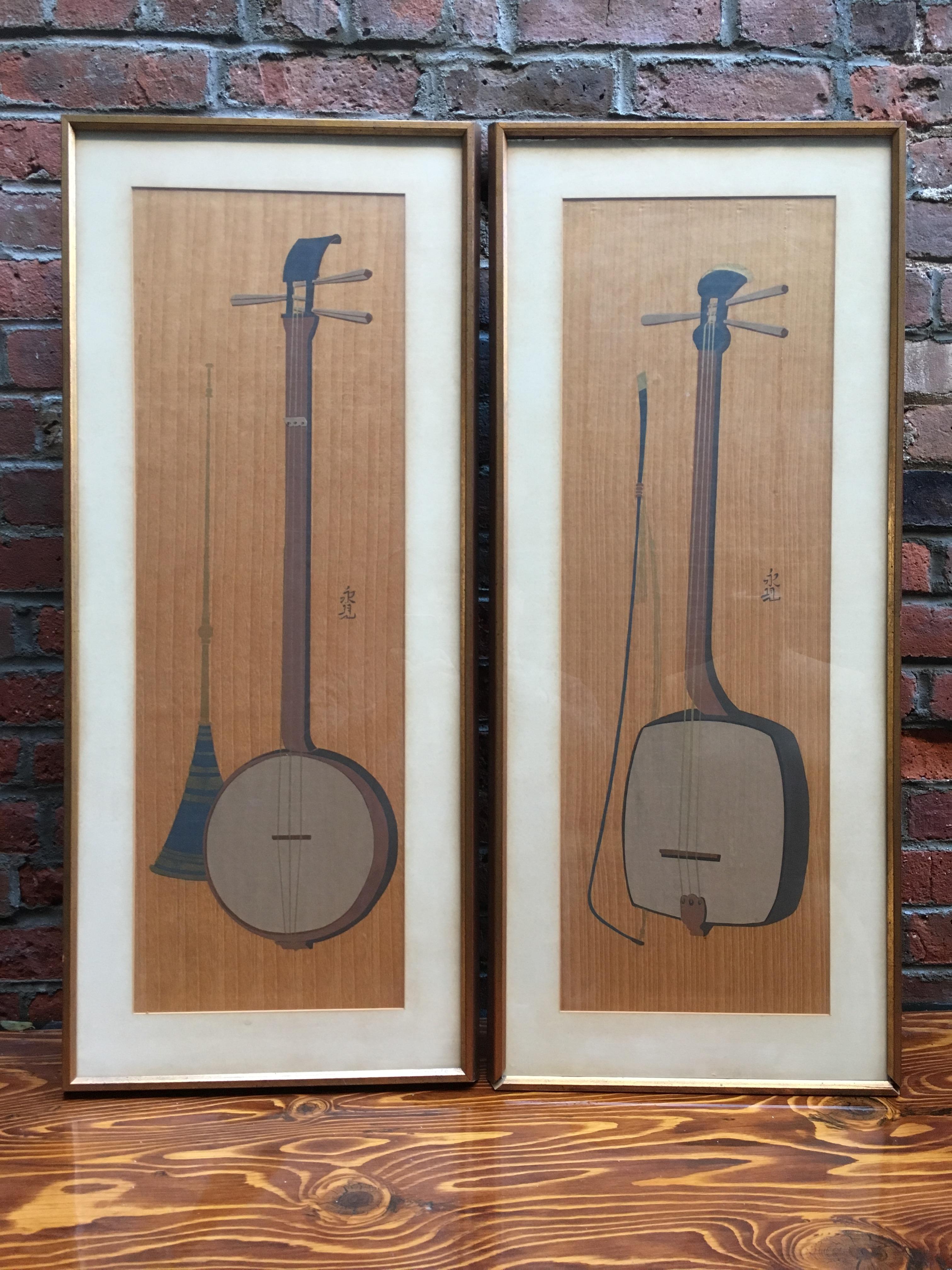 Exquisite pair of 1950s Japanese lithographs on Cherry wood veneer of the traditional Japanese three stringed instruments called Sanshin or Shamisen. Matted, glazed and framed in simple gilded wood moldings. Both are signed with Japanese characters.