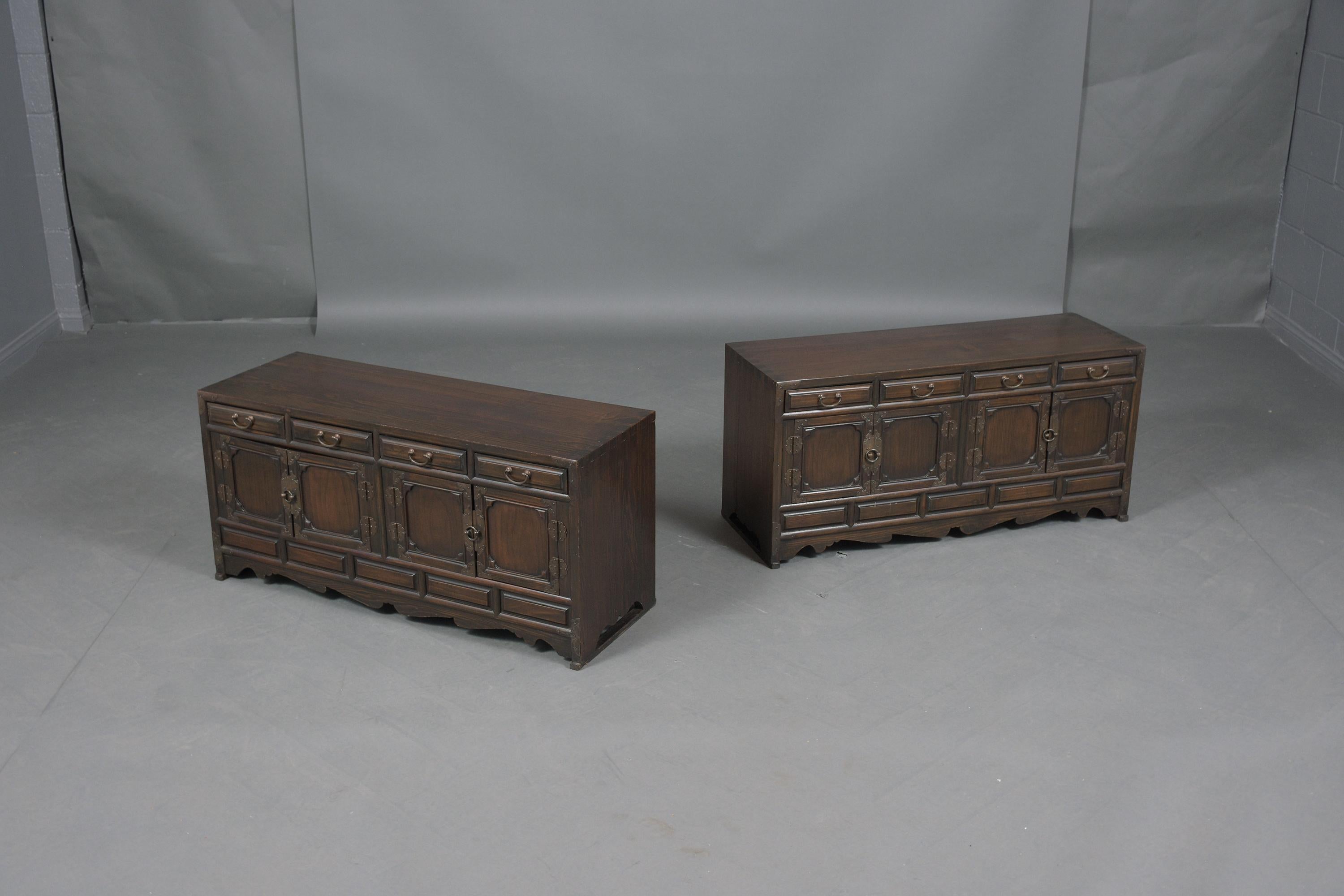 An extraordinary pair of oriental cabinets hand-crafted out of elmwood in good condition and professionally restored by our expert team of craftsmen. This fabulous pair of low dressers features a dark walnut color finish that has been only waxed and