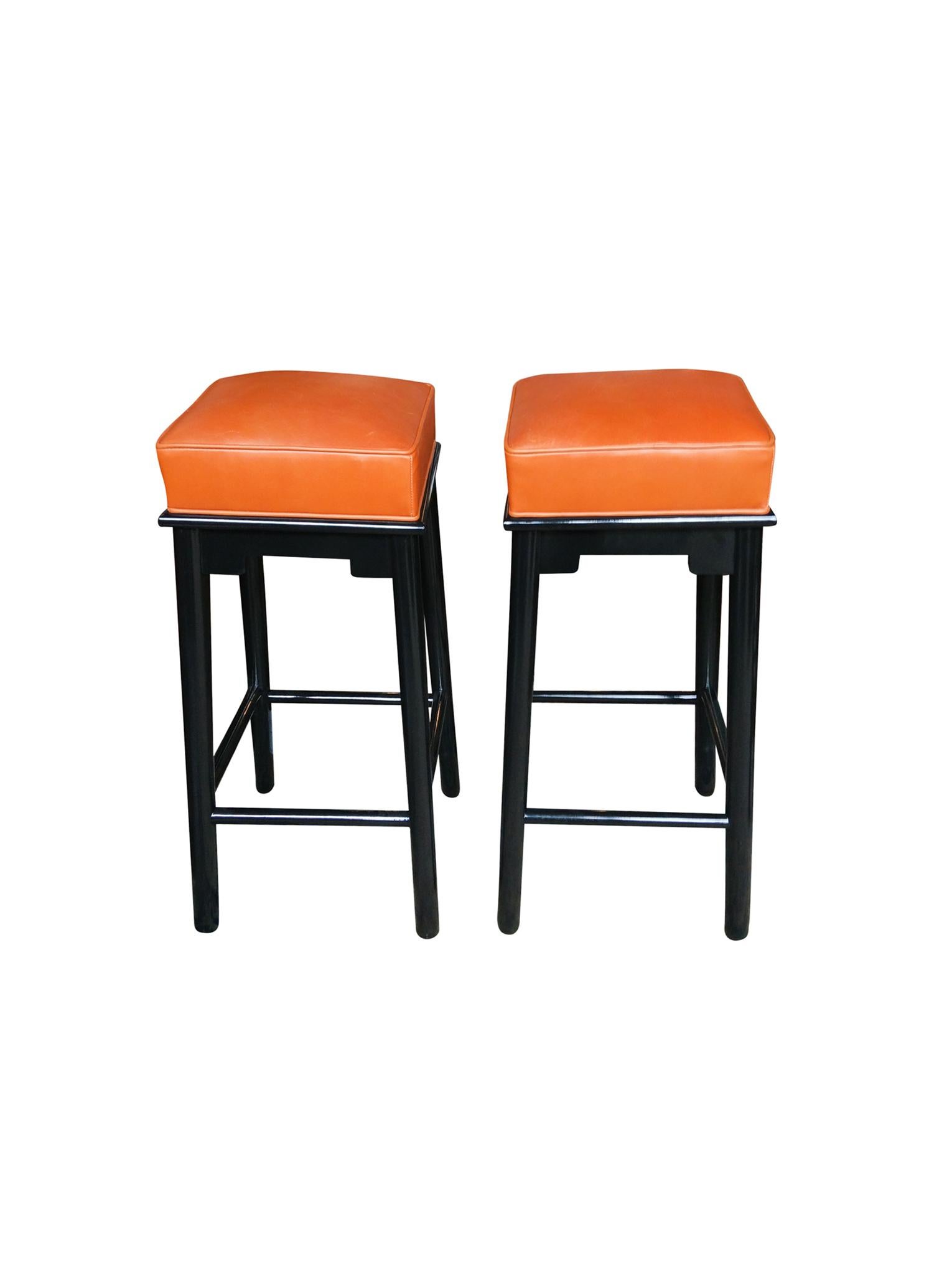 An outstanding pair of bar stools with new finish and upholstery. The stools' design is in the eccentric style of James Mont, who mixed various styles in his furniture. This pair is newly re-ecushioned and reupholstered with a vintage caramel