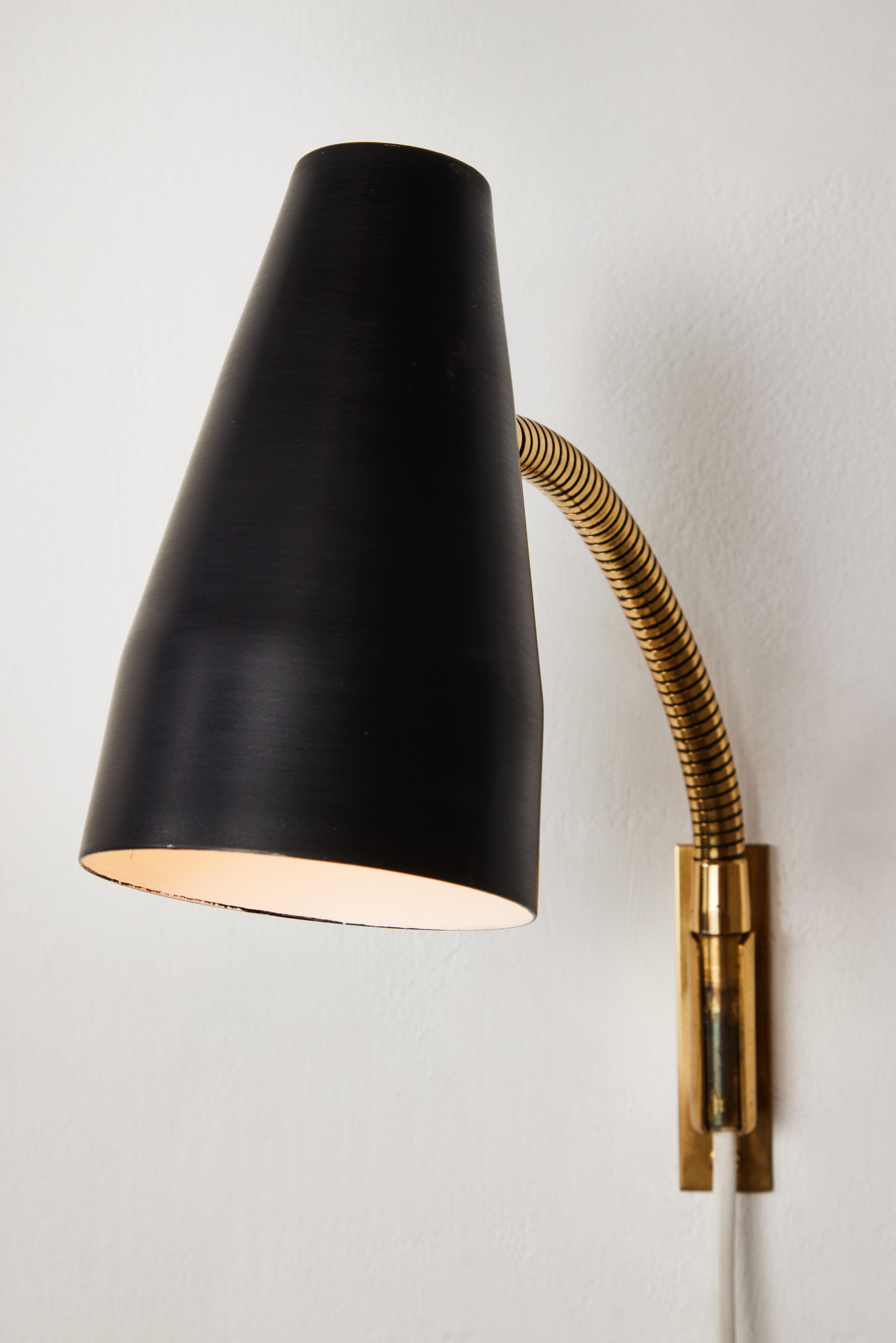 Pair of 1950s Lisa Johansson Pape Model #50-056/2 wall lights for Stockmann Orno. A highly versatile and adjustable pair of wall lights, the brass gooseneck arm with shade can be raised and lowered as well as rotated right and left. The articulating