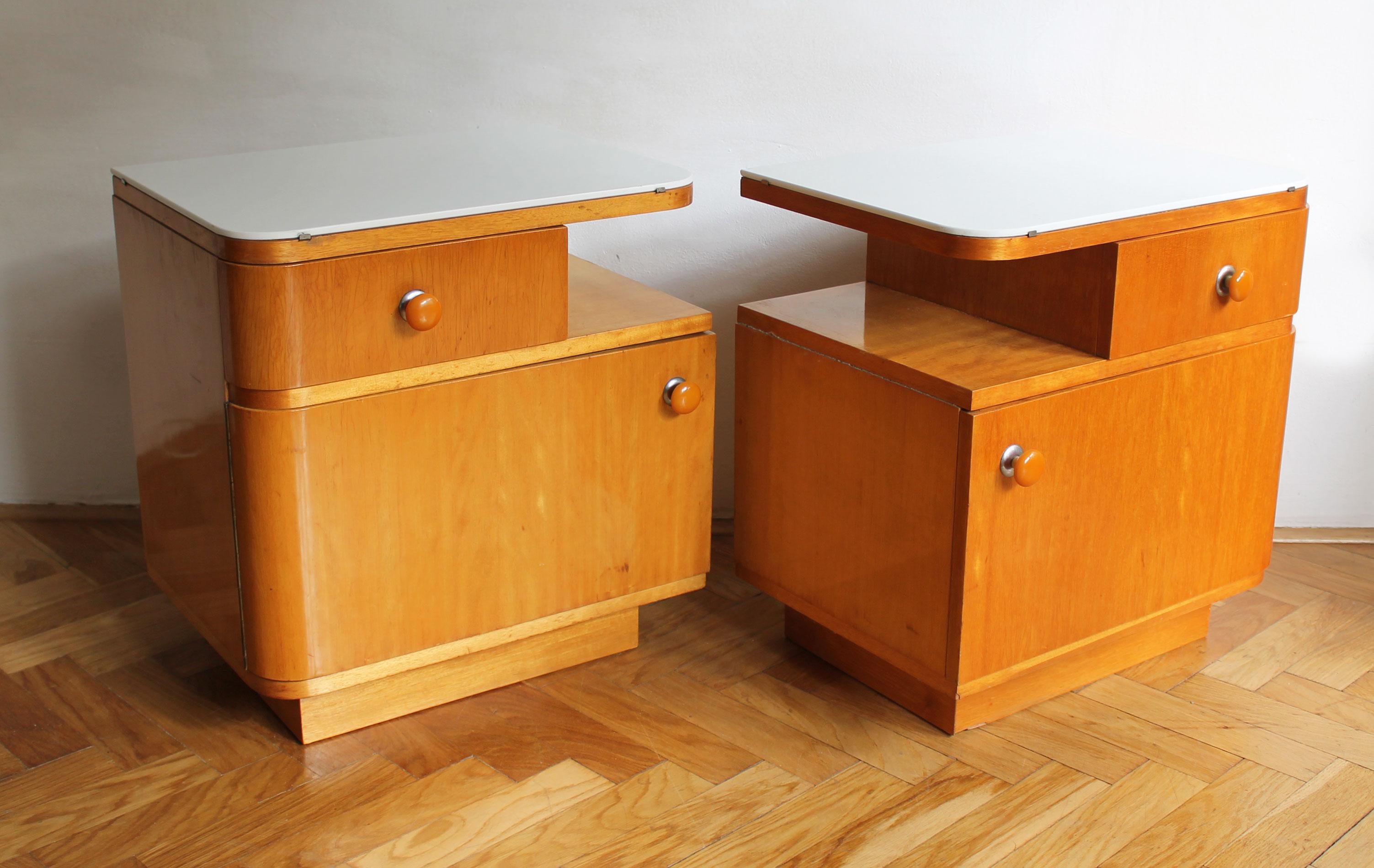 A pair of 1950’s Bedside tables made of maple wood and elegant white opaxite glass.

The bedside tables have softly curved corners on one side with a well balanced composition consisting of a large door with a smaller drawer, both with round orange