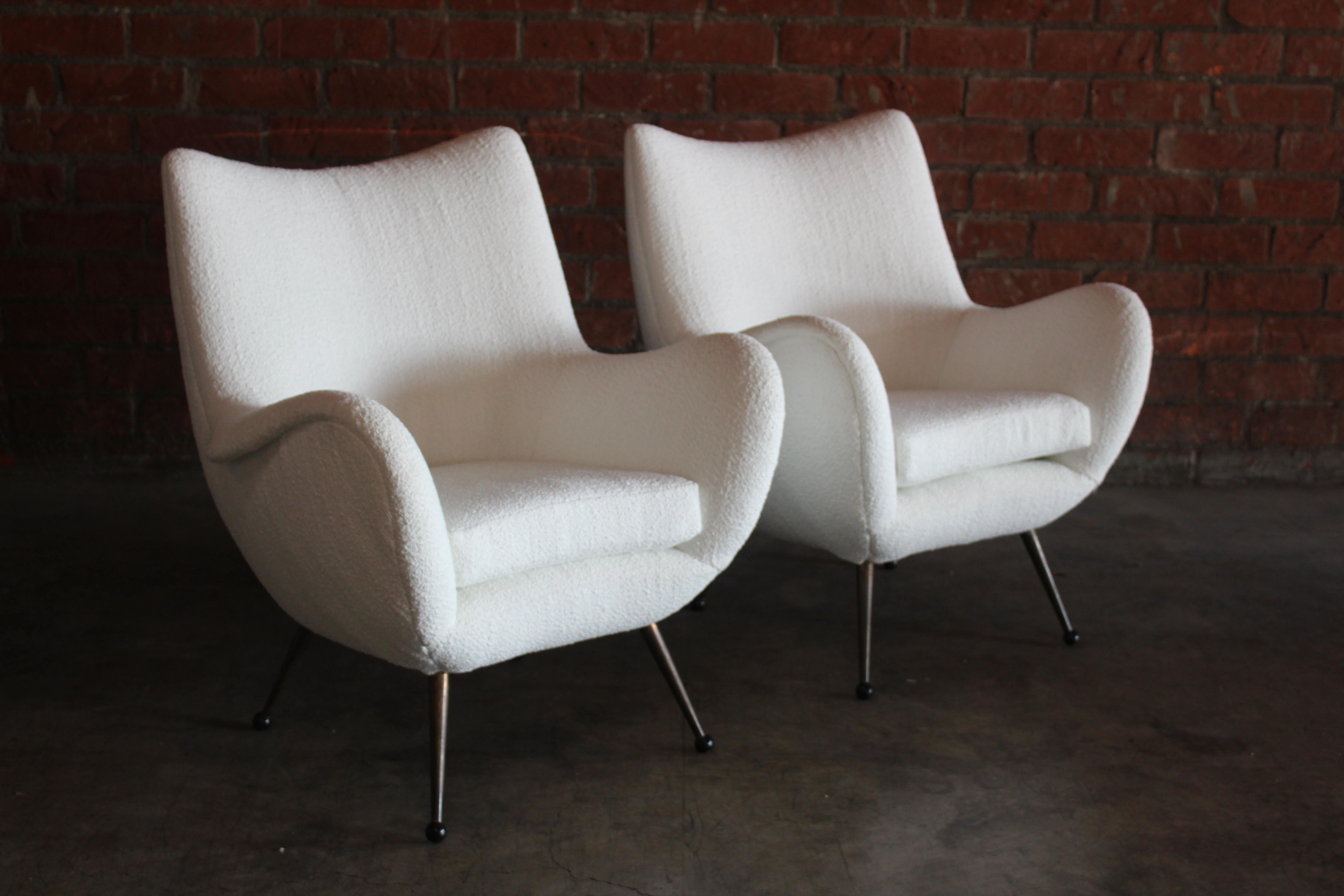 Pair of stunning vintage Italian lounge chairs from the 1950s. The pair have been fully restored and reupholstered in a Rogers and Goffigon performance boucle in white. They feature loose seat cushions and brass legs with plastic sabots. They are in