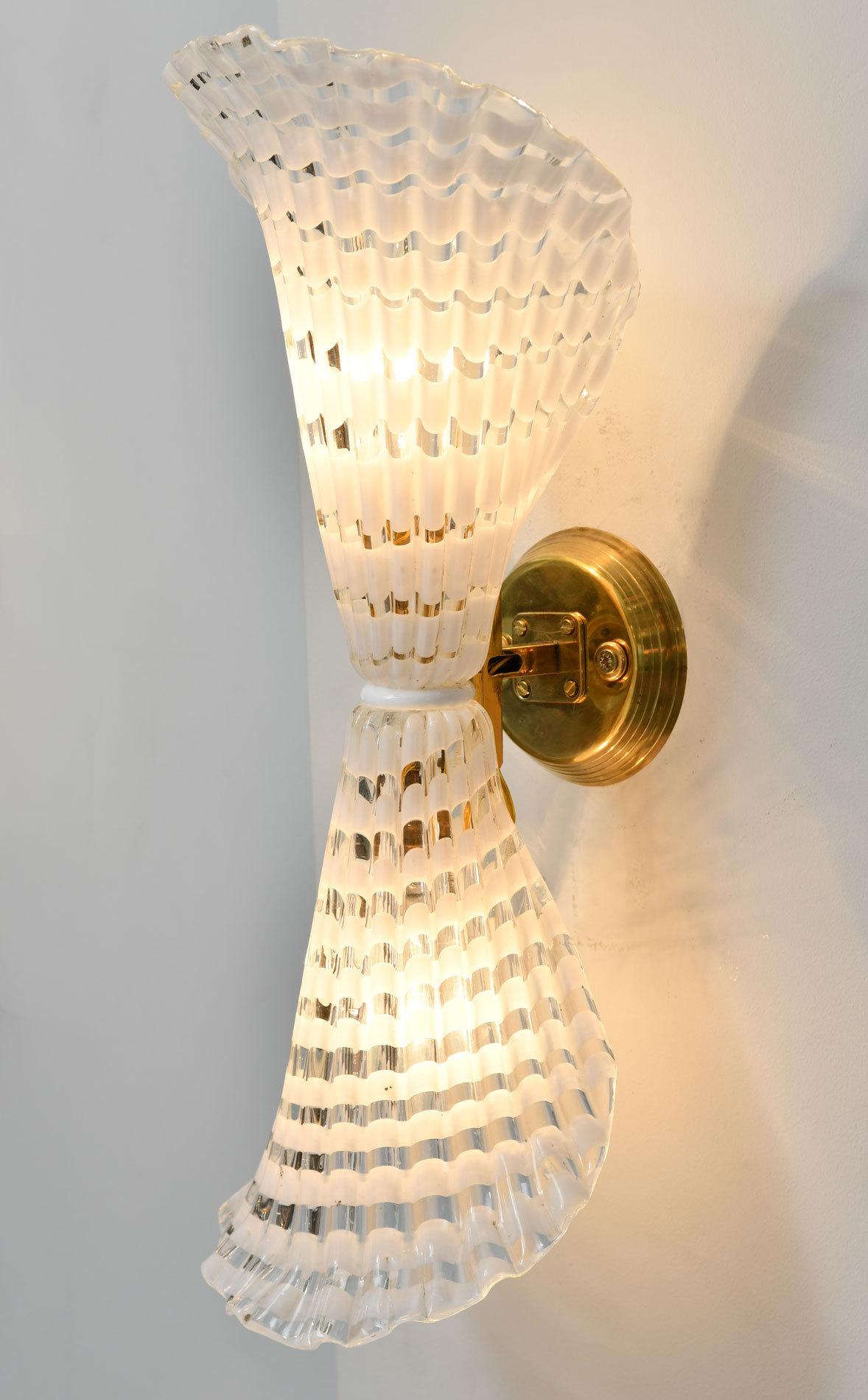 Hand blown fluted Murano wall lights in clear and white stripes with central white ring. The brass wall mount sits proud of the wall and can be arranged horizontally as a bow or as shown.
