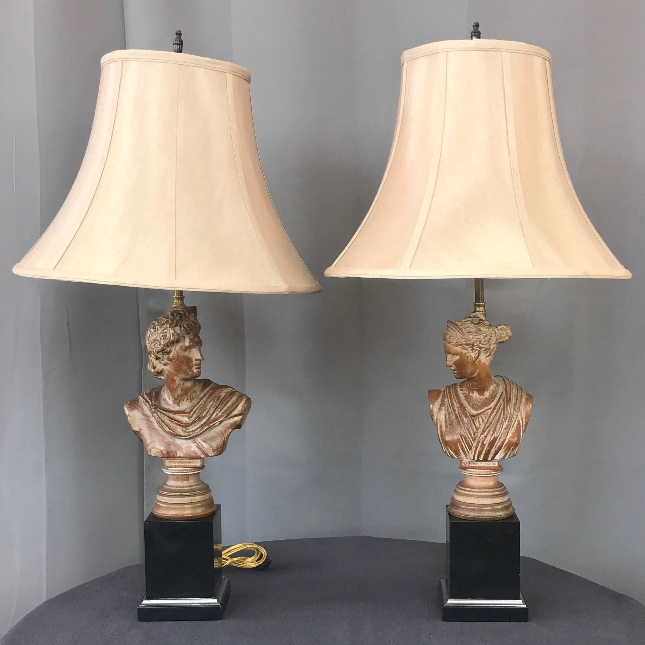 A pair of 1950s neoclassical roman bust “His & Her” hand-carved chestnut and lacquered wood table lamps.

Exquisitely carved solid chestnut busts depicting a stoic man and woman in Roman garb proudly posed atop turned bases. Judiciously applied