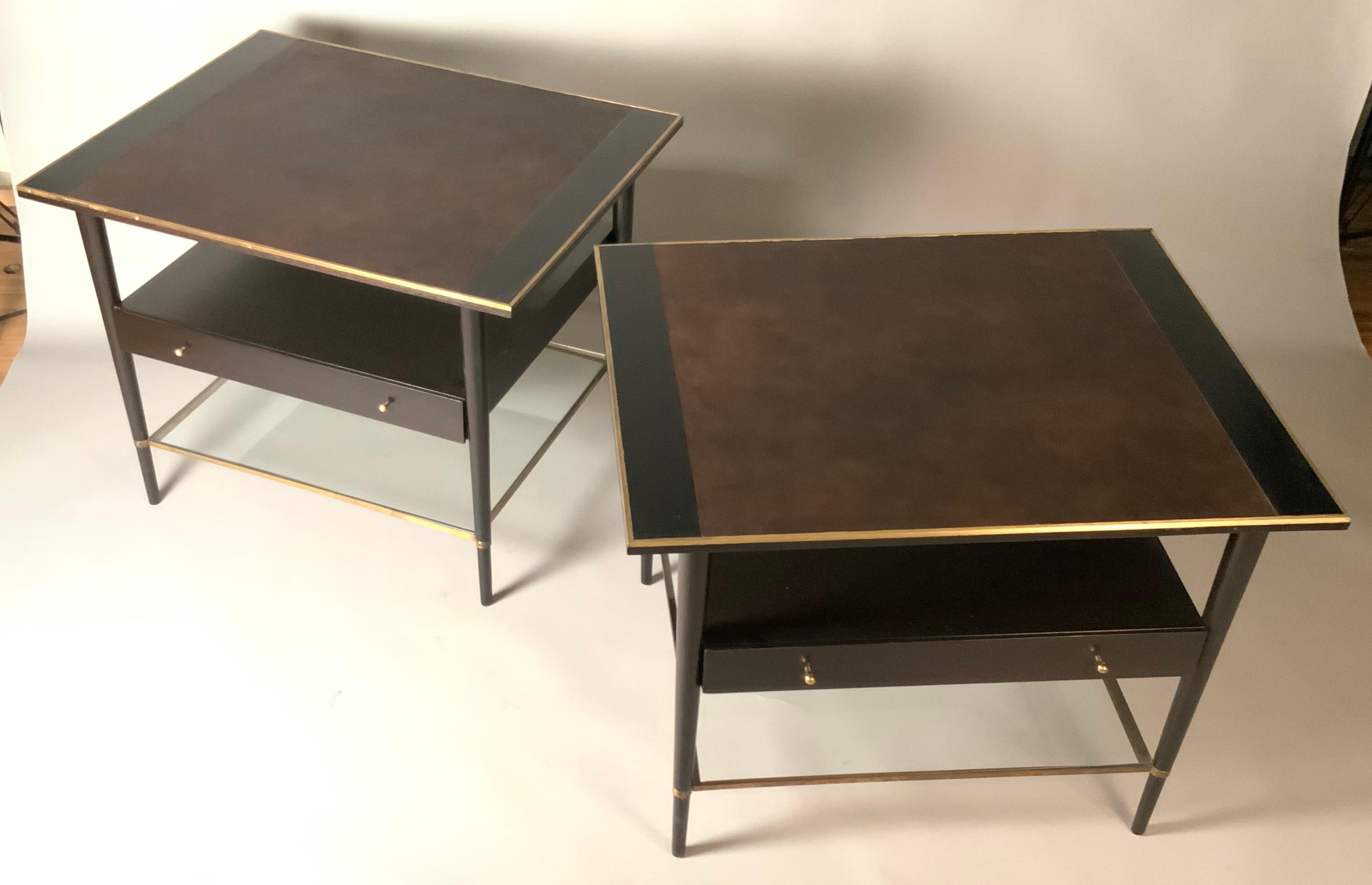 A pair of very handsome 1950's nightstands by Paul McCobb for Calvin. Beautiful design and scale, with mahogany cases, leather top, brass trim, and a lower glass shelf. Each table has a single drawer as well. beautifully restored with an ebonized