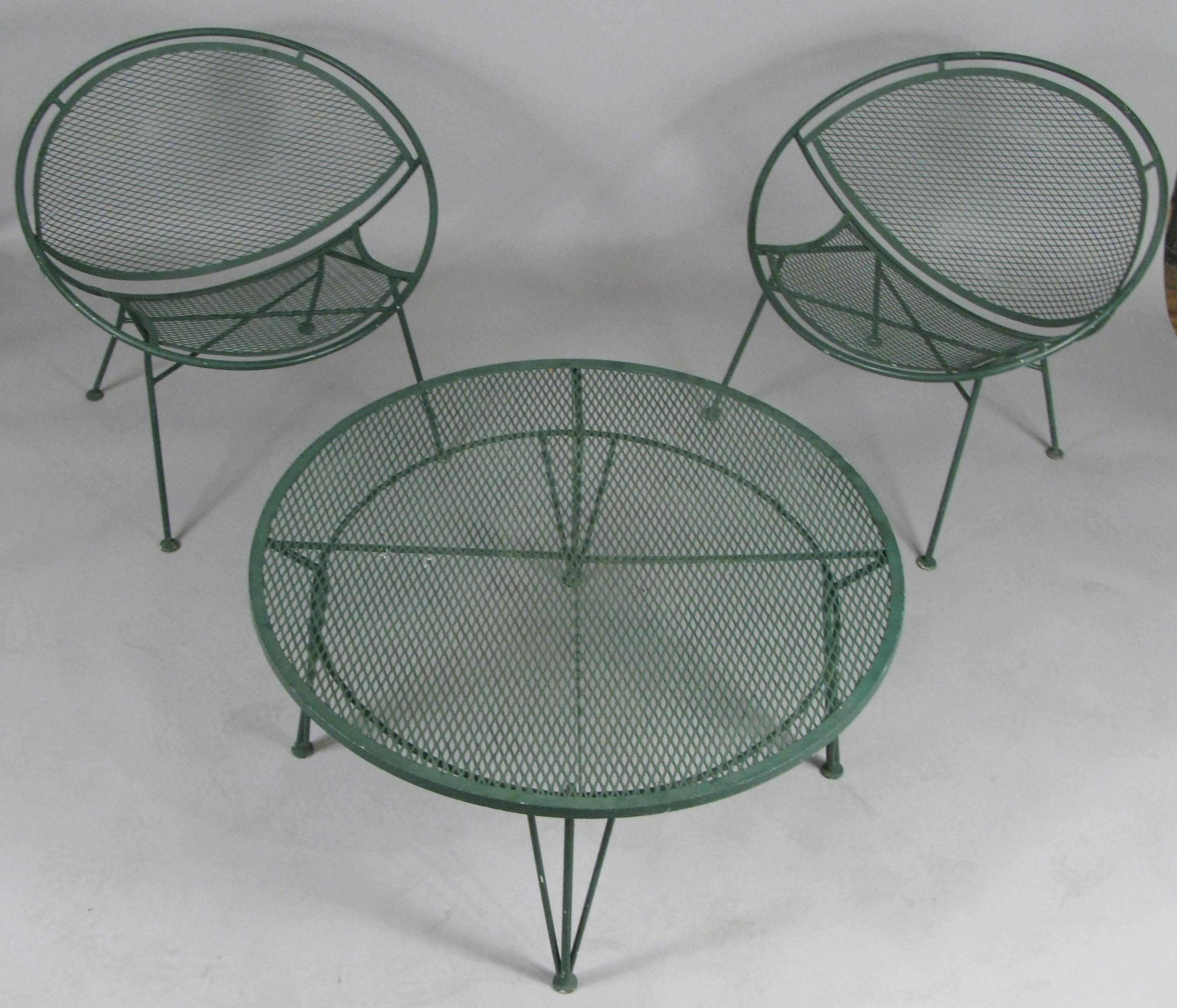 A pair of vintage 1950s wrought iron Radar collection lounge chairs and round companion coffee table designed by Maurizio Tempestini for Salterini. Beautiful design and very comfortable and in their original forest green painted finish. The coffee