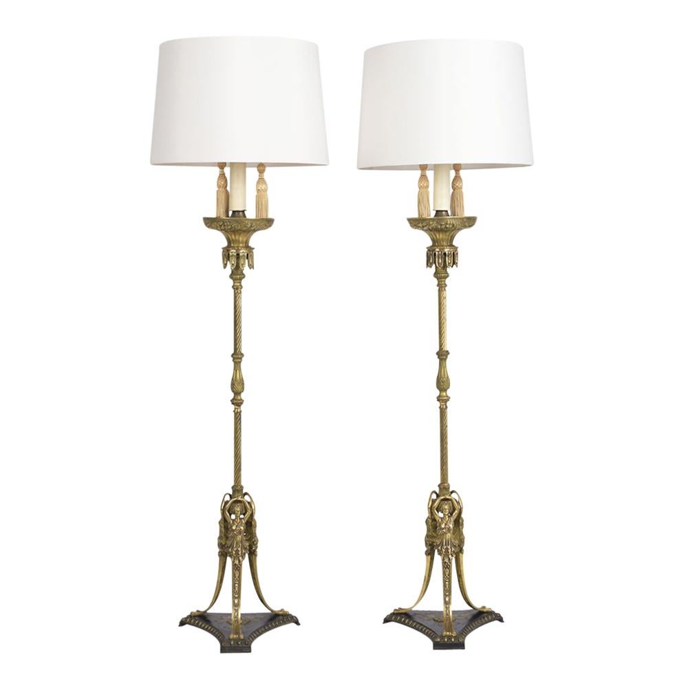 Pair of Regency-style floor lamps made out brass featuring a beautiful design on the base an brass details along with the lamp these pair come with two lights brass finials on top and a new shade in ivory color the lamps are wired and a working