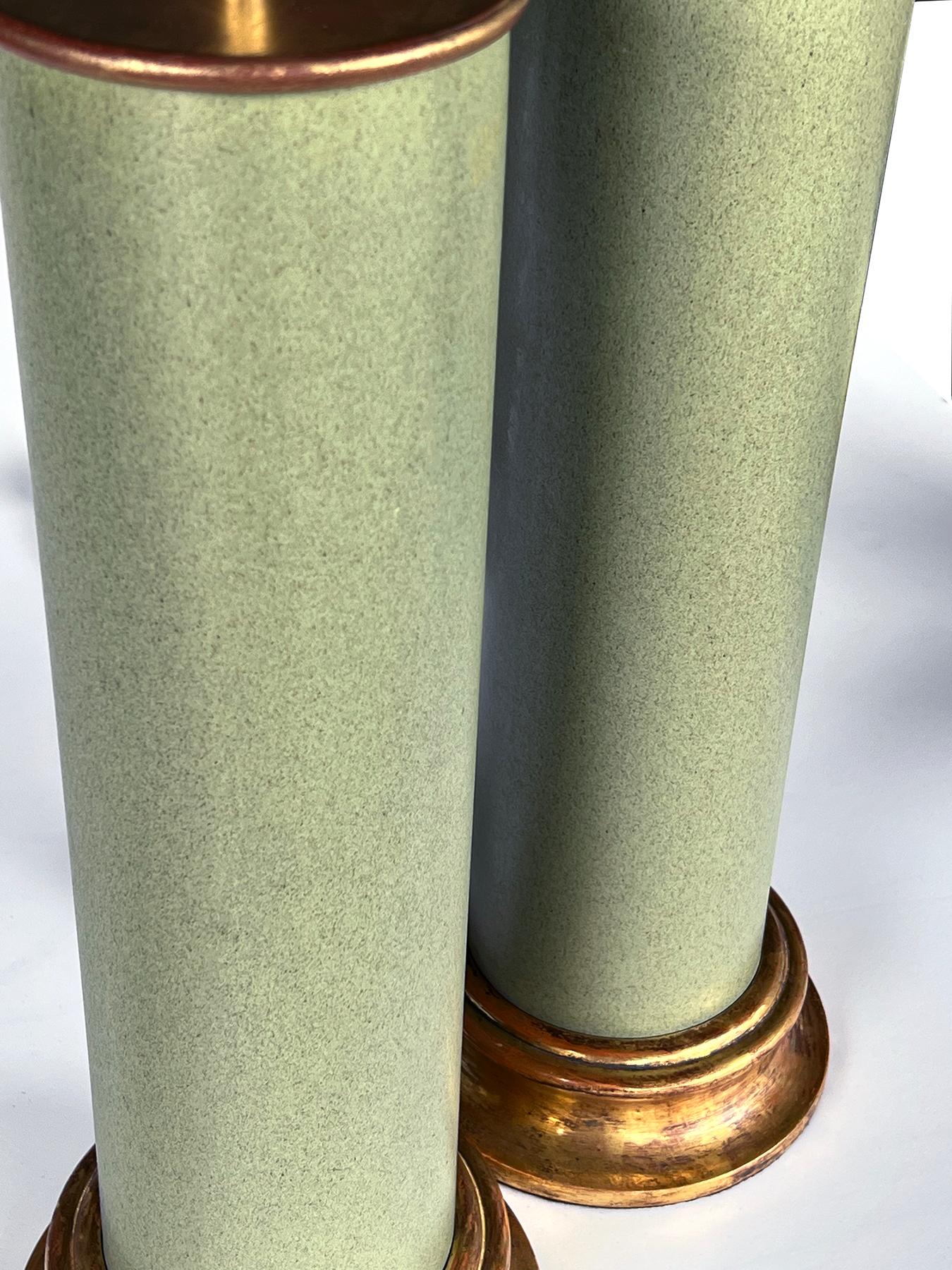 chacune de forme cylindrique simple recouverte d'une glaçure vert céladon tachetée ; avec des bases en bois doré personnalisées et des capuchons en métal doré ; 17,5