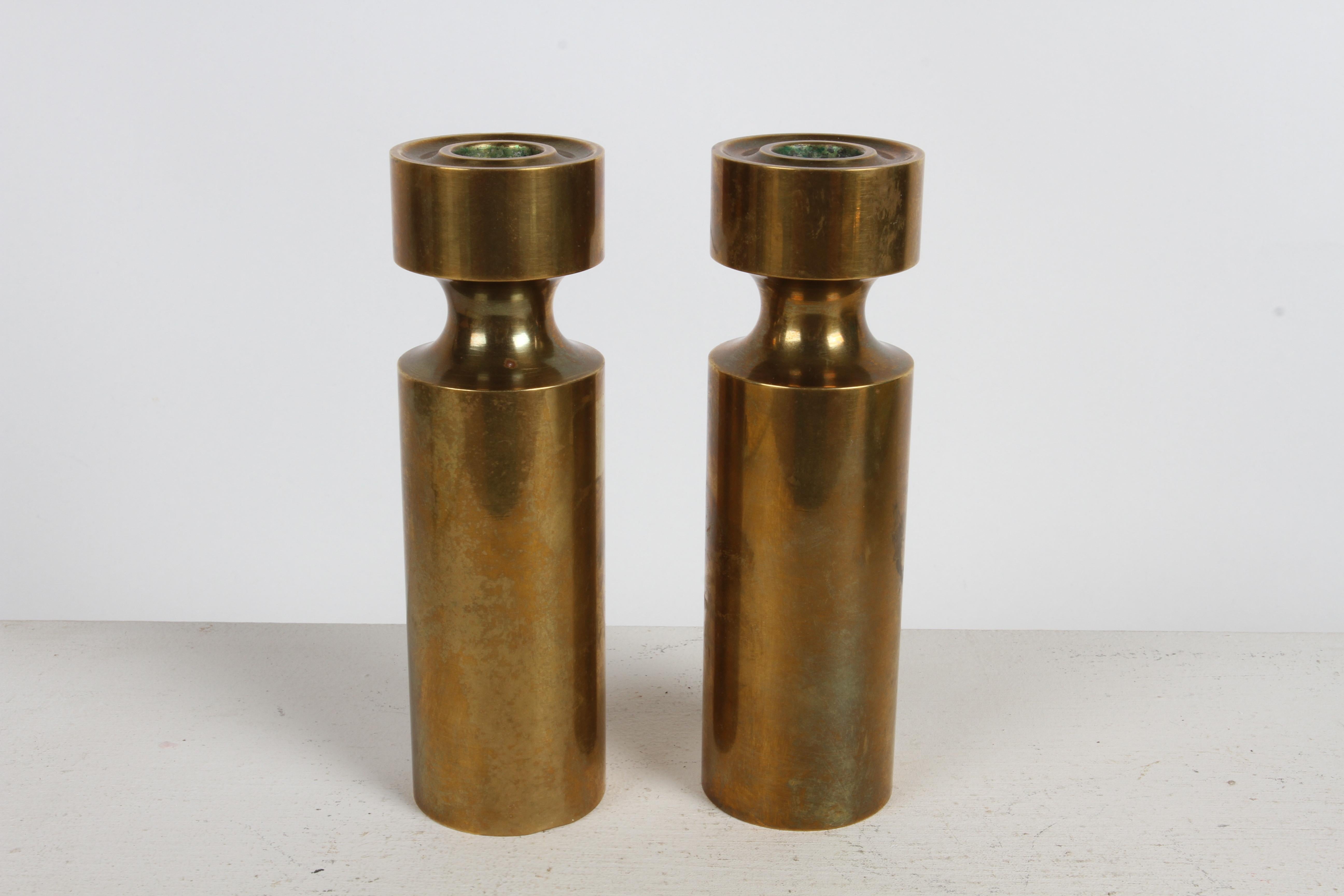 Pair of 1950s extremely heavy Scandinavian solid bronze cylinder form candlesticks or candle holders with recessed area towards top , stamped on the bottom : Made in Norway with unknown logo. 

Similar to Dansk - Denmark , Staffan Englesson of