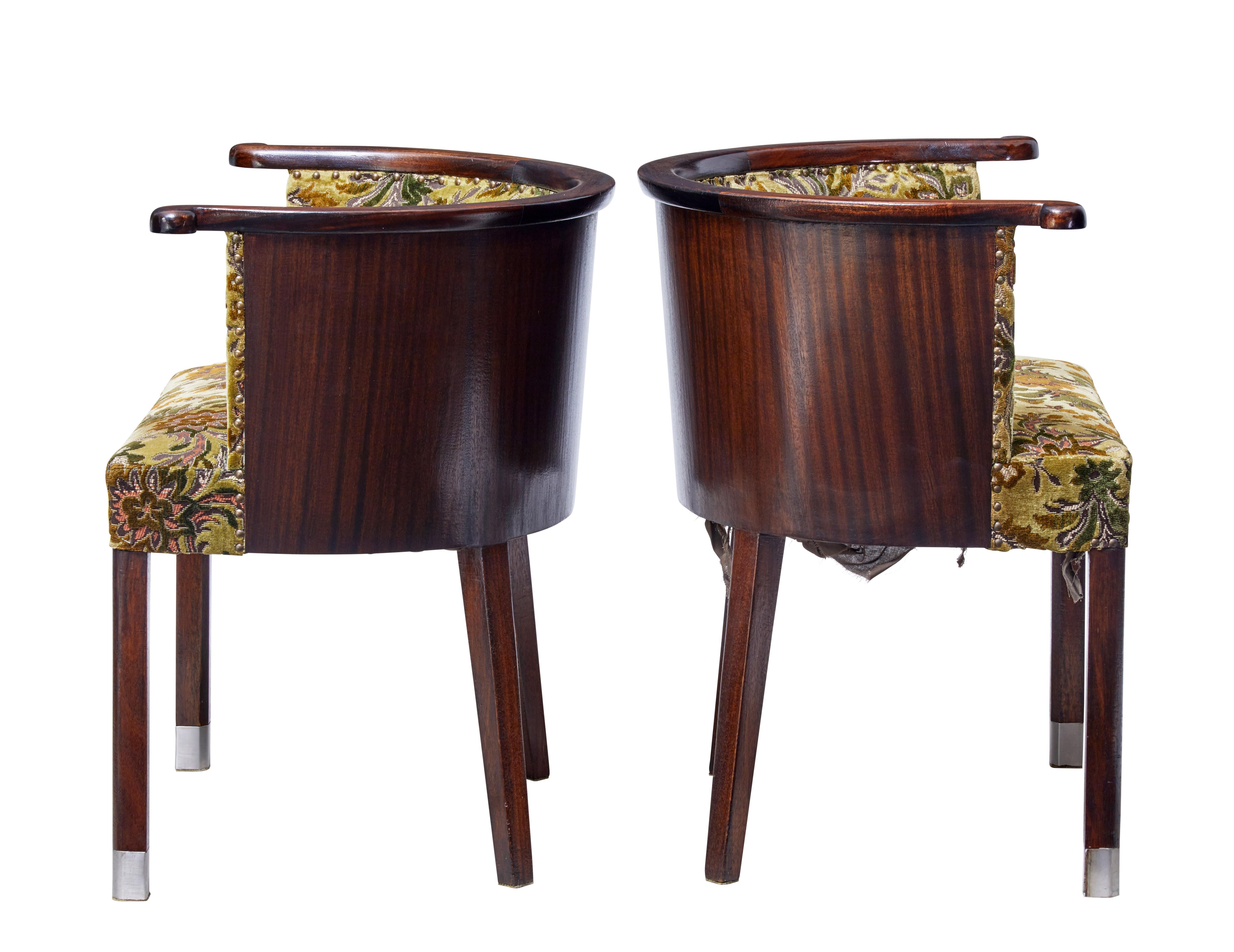 Unusual pair of 1950s tub chairs, circa 1950.

Shaped horseshoe top armrest, with shaped half moon mahogany veneered back.

Standing on block legs, with stainless steel tipped front feet.

Original floral upholstery.

Measures: Seat height: