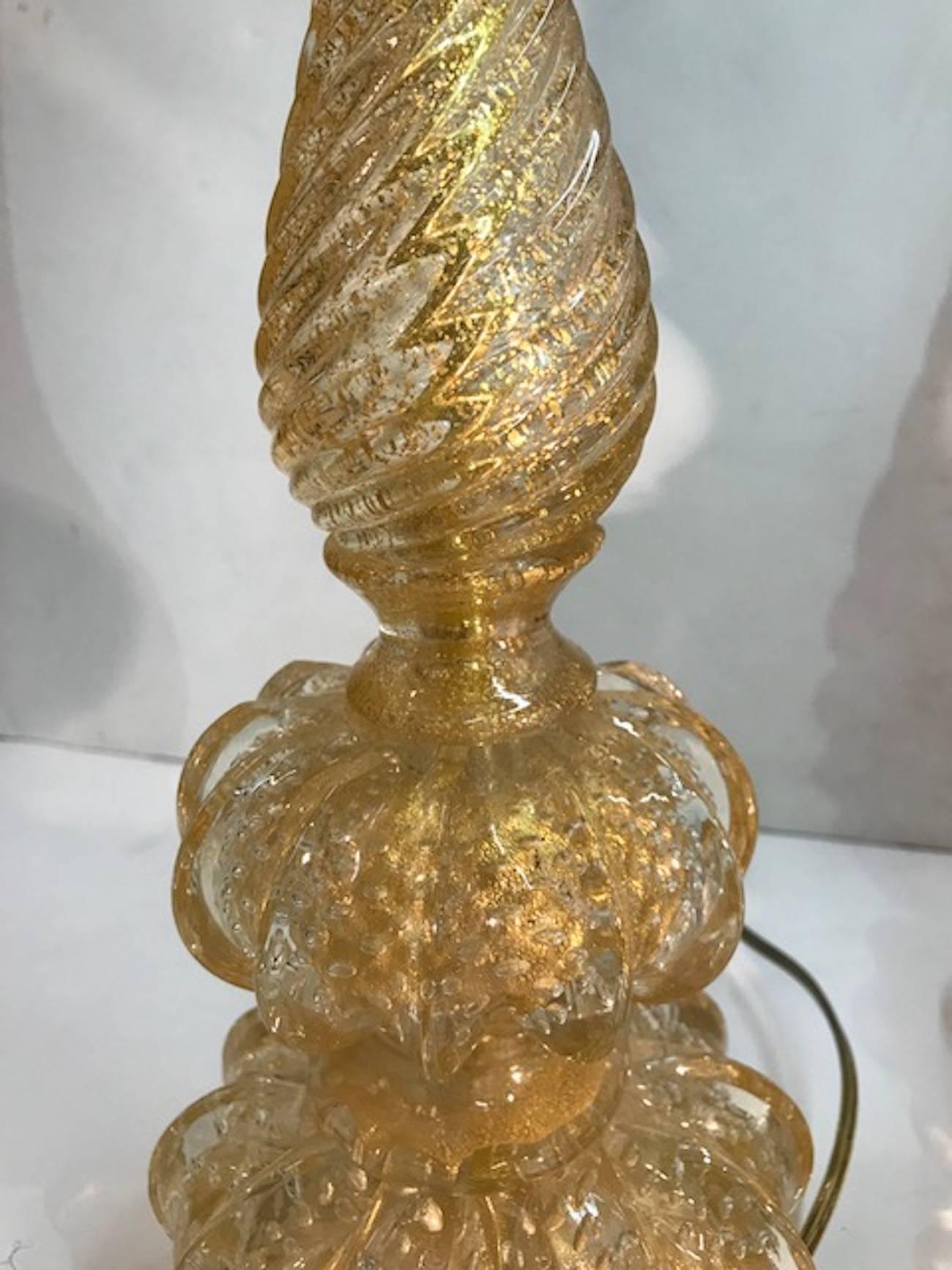 A lovely pair of 1950s Venetian table lamps produced on the island of Murano and attributed to the Seguso glass house. Hand blow in clear with gold flecks known at aventurine glass. Bases of lamps have engineered pattern of internal bubbles. The