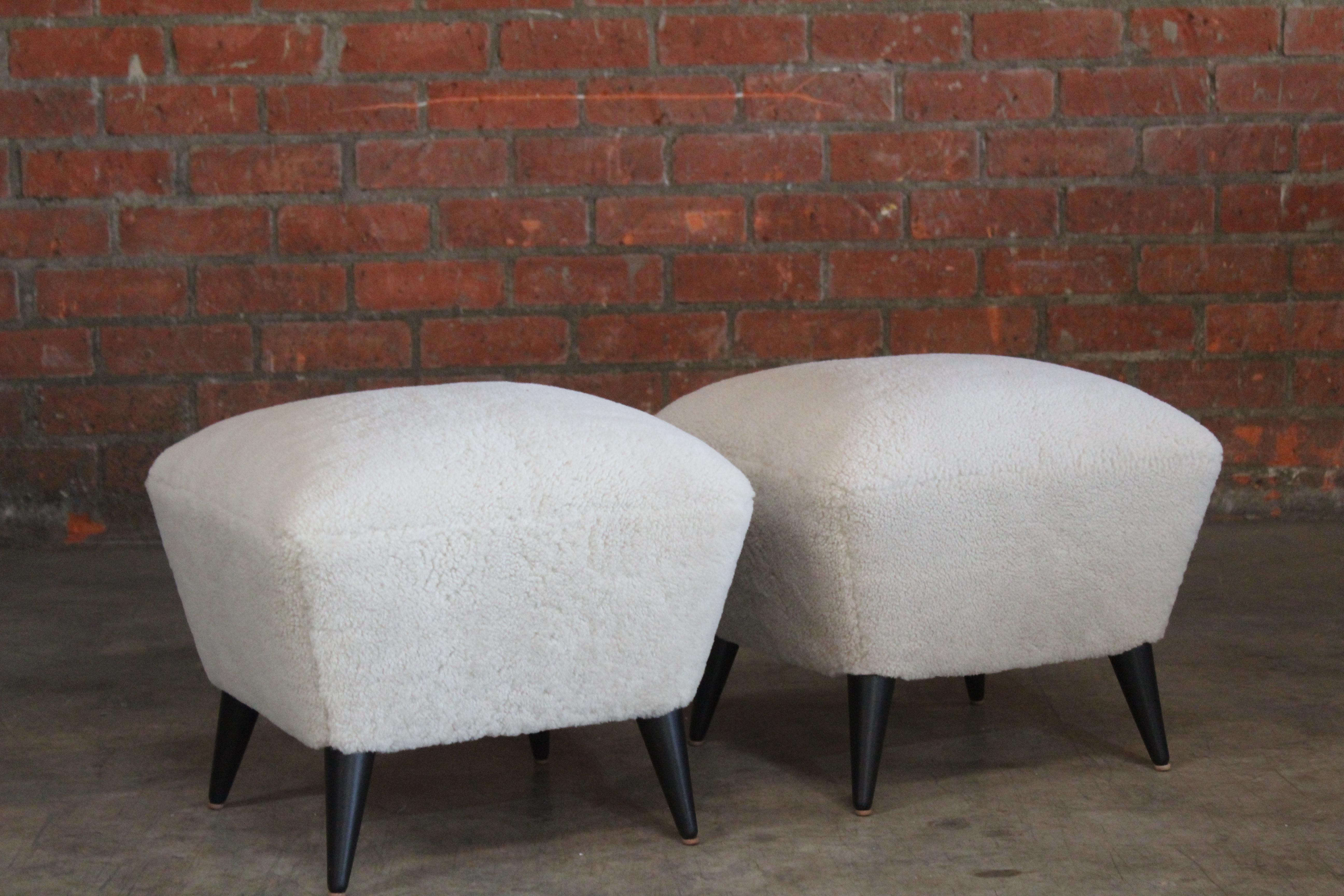 Pair of vintage ottomans by Henri Caillon for Erton, France, 1956. The pair have been completely restored and reupholstered in sheepskin hides. The walnut legs have been refinished satin black. Original tags still present. Sold as a pair.
