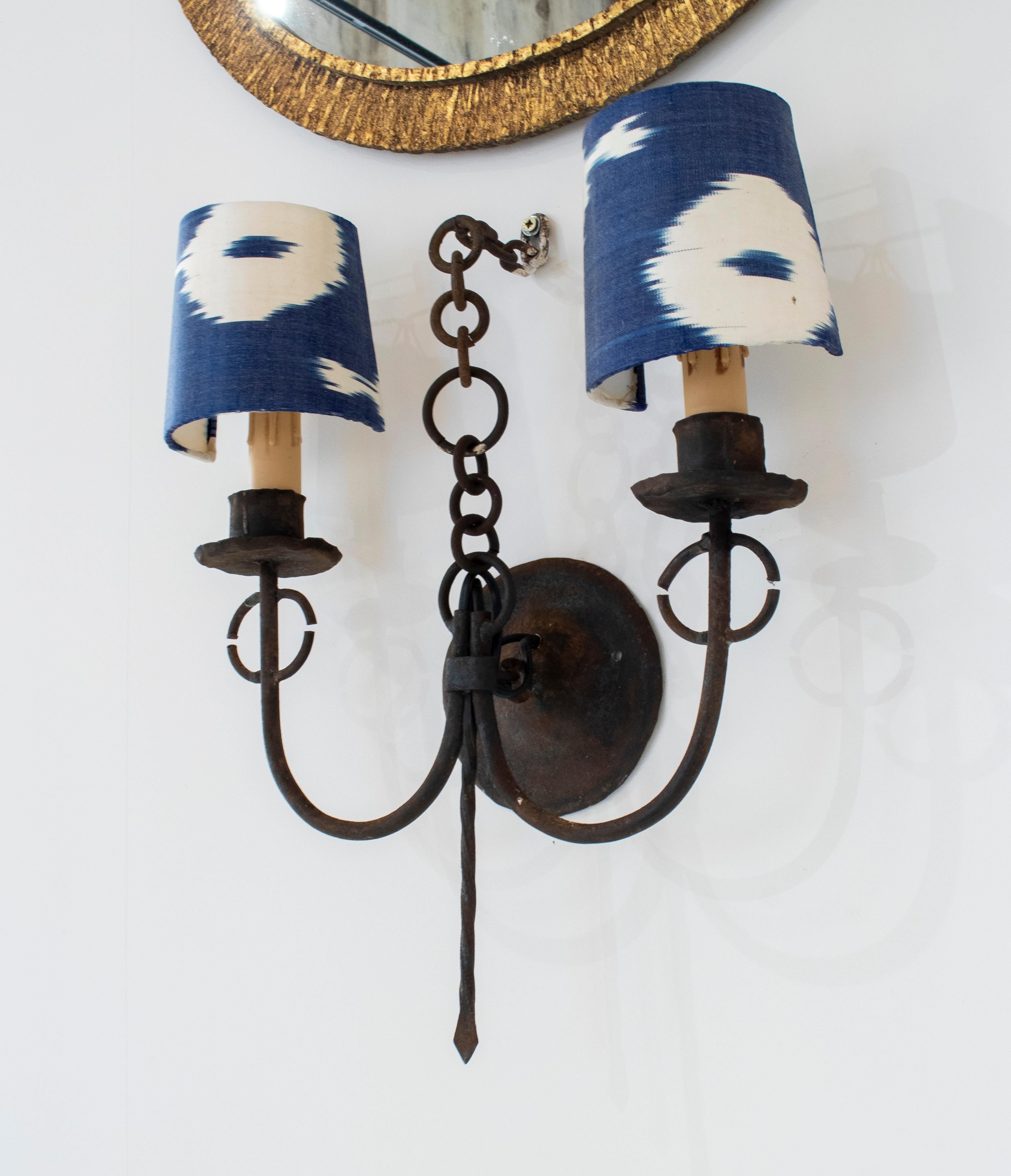 Pair of vintage 1950s Spanish 2-arm iron sconce wall lamps with upholstered lampshades.