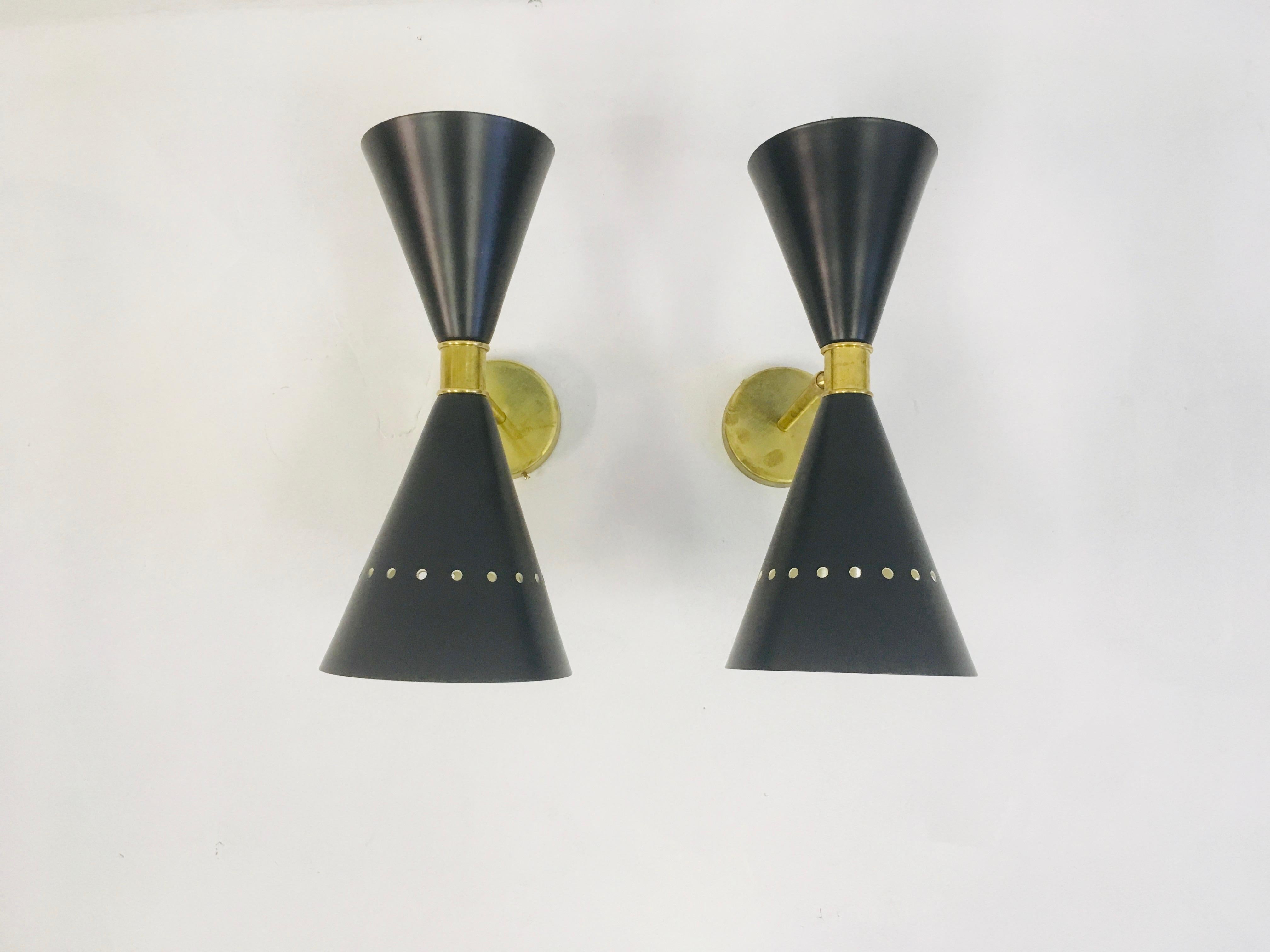A pair of wall lights
Black lacquered metal
Brass band and fittings
Adjustable
1950s style
Made in Italy
Price is for a pair
Larger quantity can be ordered.