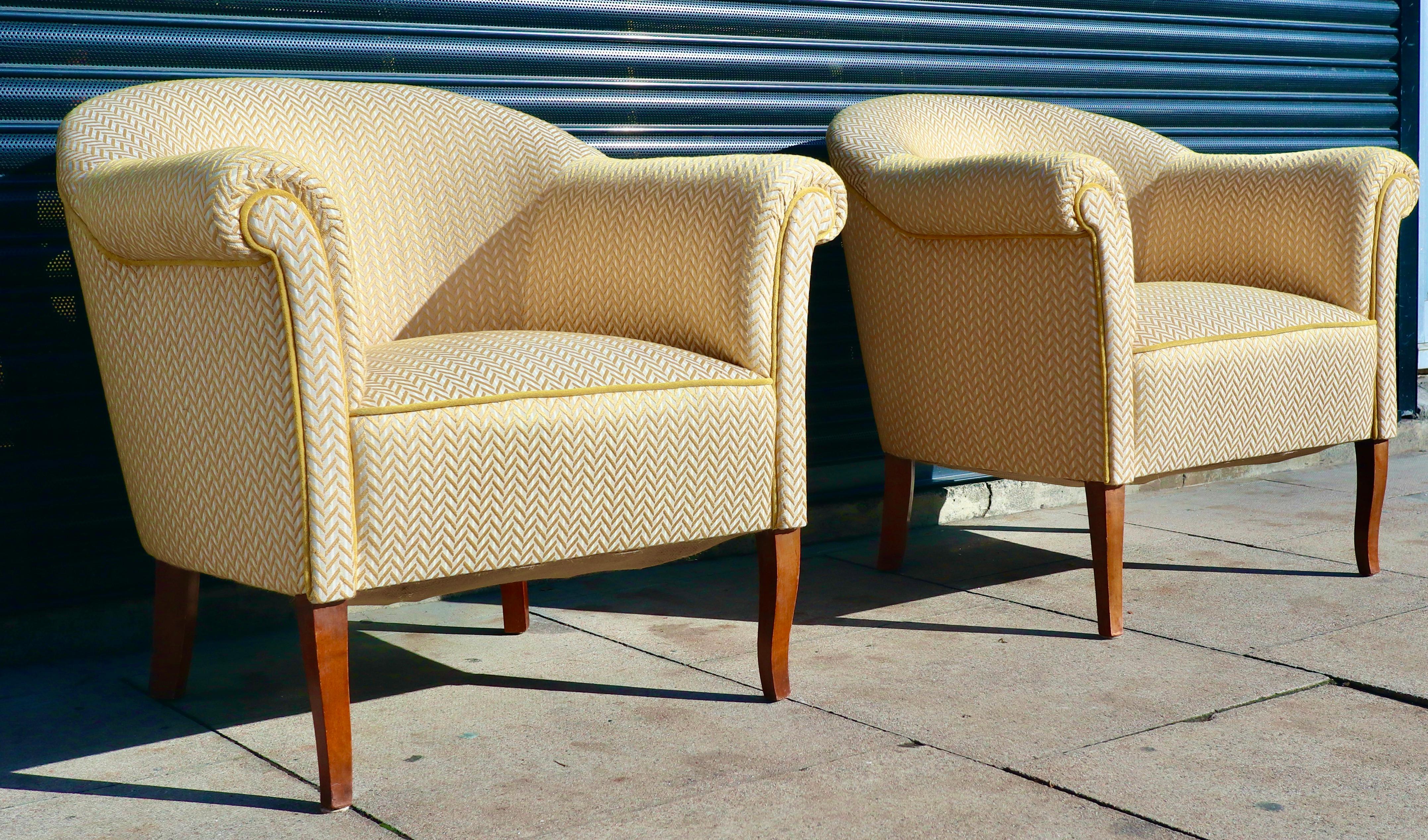 A classic pair of Swedish 1940s/50s armchairs on carved stained beech legs.  These quality chairs have been upholstered in quality yellow coloured herringbone textile.  Both armchairs are sprung and are extremely comfortable in addition as being