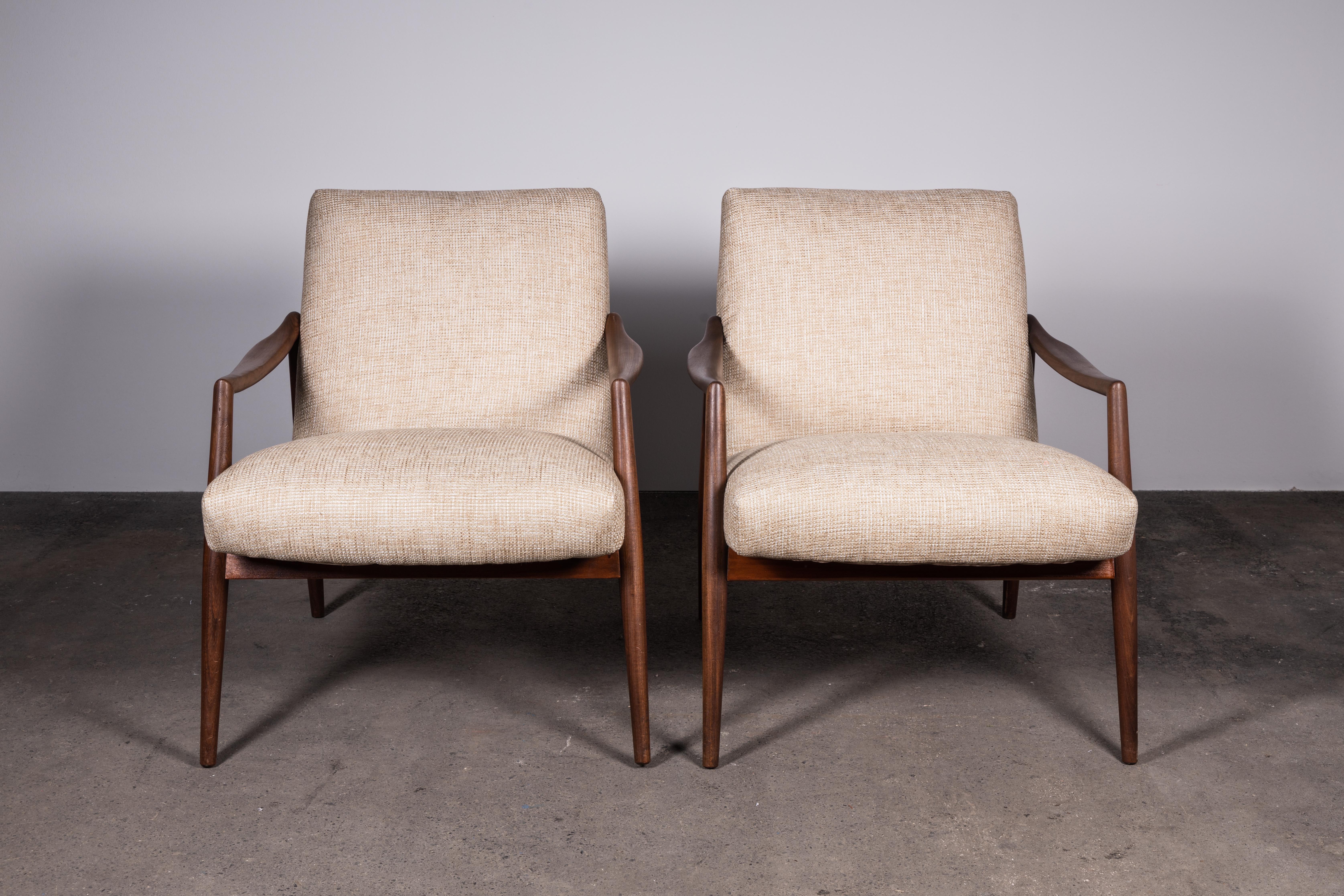 The epitome of Mid-Century Modern refinement. This iconic pair of low-back teak armchairs are some of the best design and craftsmanship of the era. 

The sculpted teak wood, elegantly darkened with age, is complemented by chic tweed upholstery à