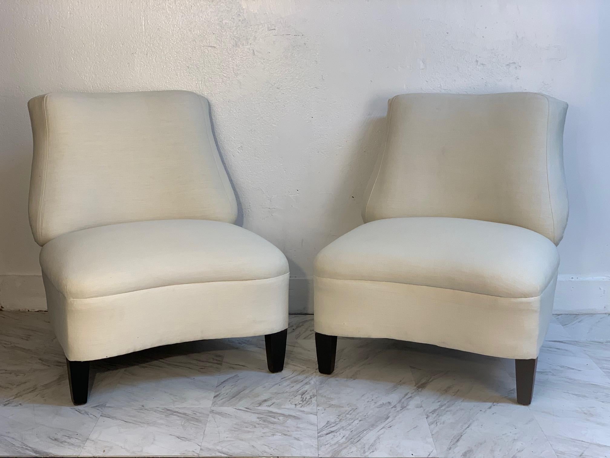 Pair of 1950s lounge or slipper chairs in the manner of Gilbert Rohde. Off-white upholstery with black lacquered wood legs. Dunbar style.