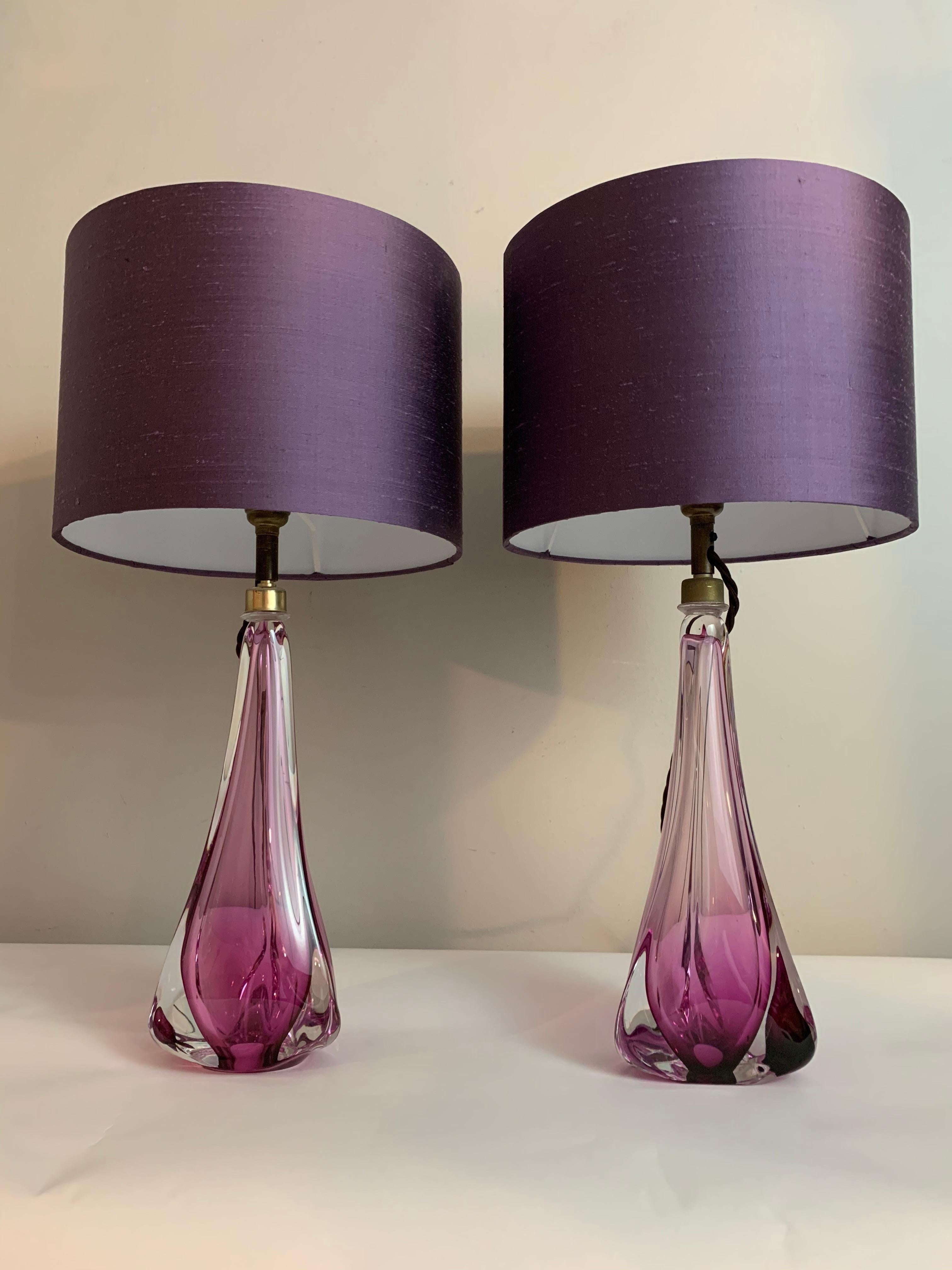 A pair of triangular 1950s Belgium Val St. Lambert purple and clear glass lamp bases including new silk shades. The lamps are a striking deep purple towards the base with thick clear glass on each corner. 

The lamps have the same design but as