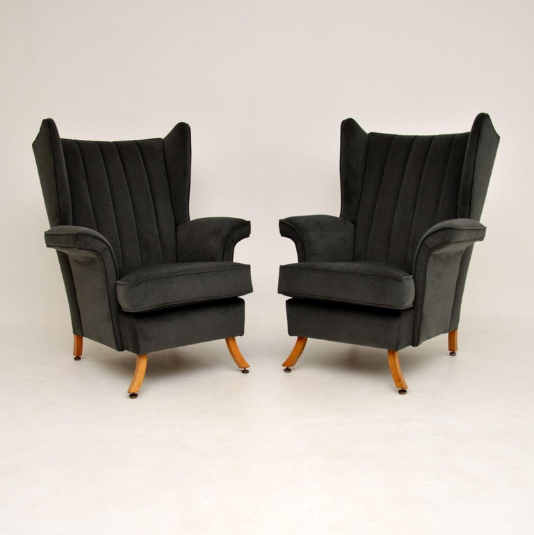 A stunning and very unusual pair of wing back armchairs, these date from the 1950-60’s. They are of generous proportions and are very comfortable.

They have a wonderful shape, with scalloped backs, curve over arms and beautiful splayed solid elm