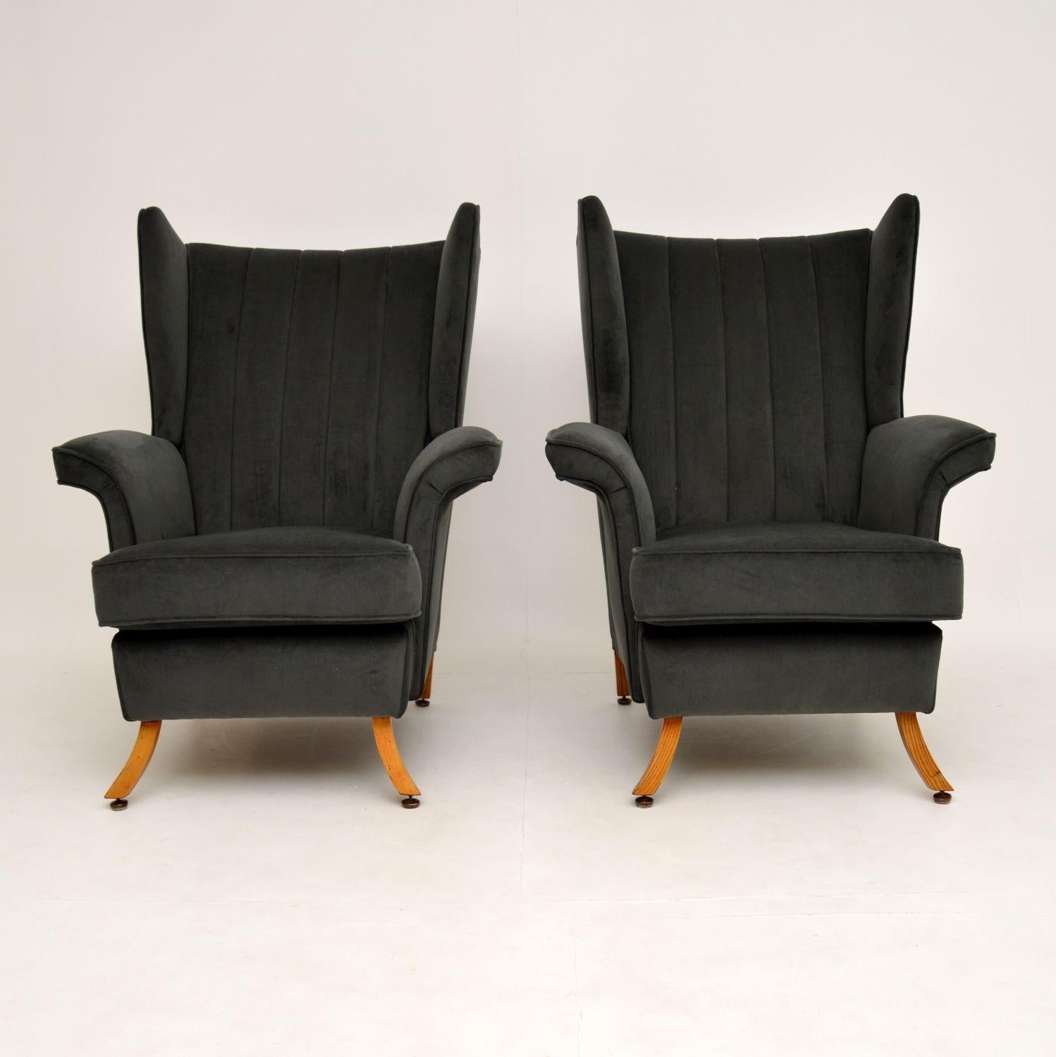 A stunning and very unusual pair of wing back armchairs, these date from the 1950-60’s. They are of generous proportions and are very comfortable.

They have a wonderful shape, with scalloped backs, curve over arms and beautiful splayed solid elm