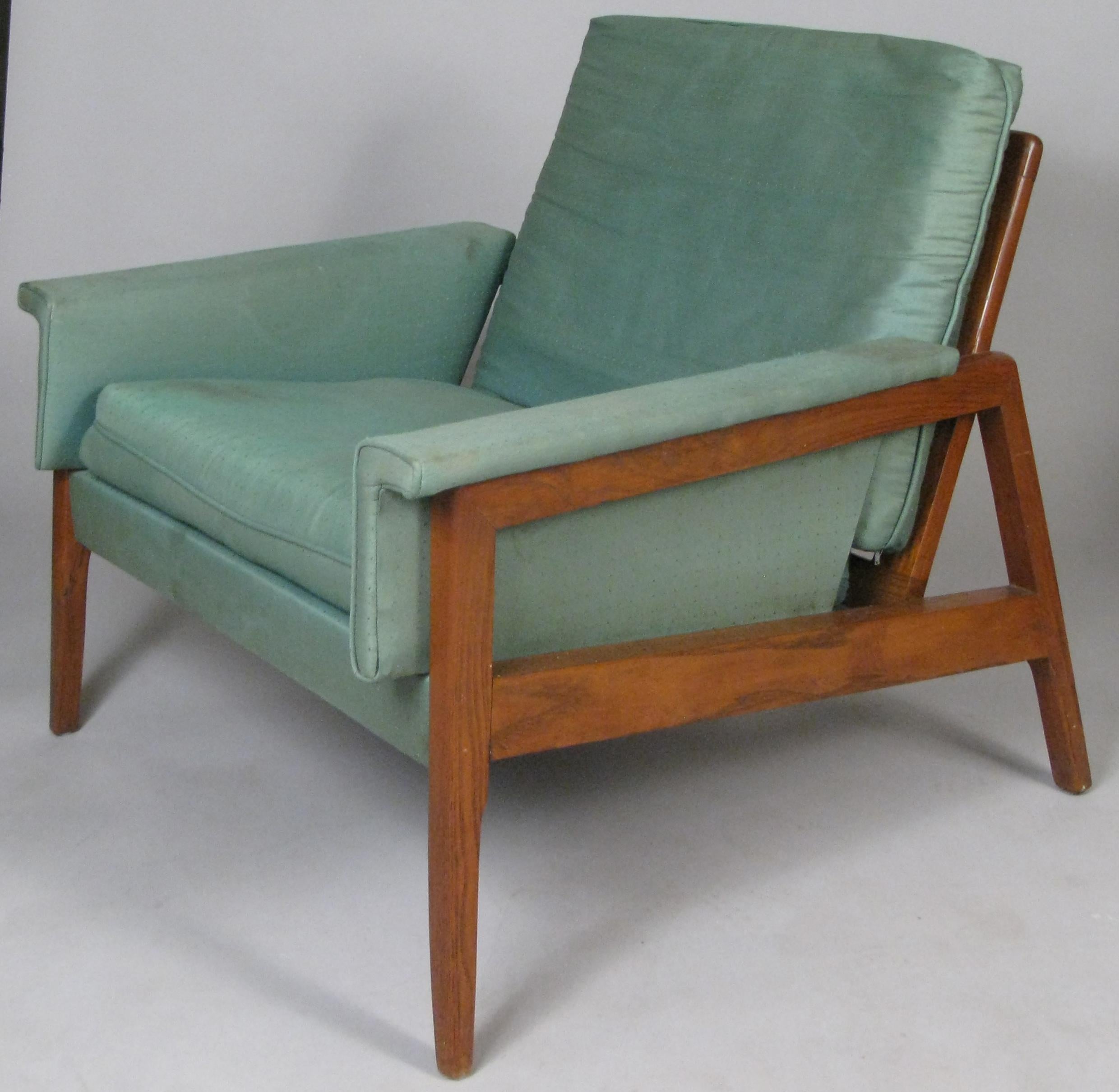 A pair of very handsome vintage 1950s American walnut frame lounge chairs, with angled legs and nice detail with the arm wrapping over the frame. These are in their original green silk upholstery, which is worn and will need to be reupholstered.