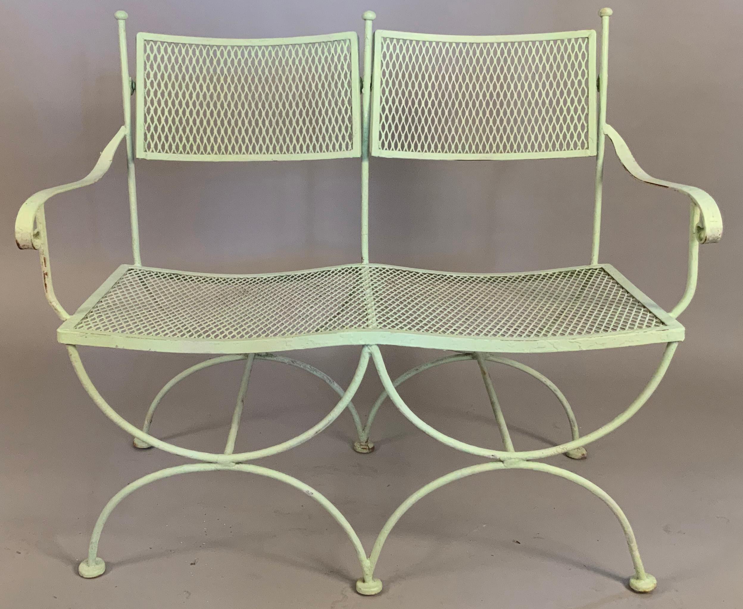 A pair of elegant vintage 1950's wrought iron benches with curule bases and articulated tilting seatbacks. Beautifully scaled with nice details, in their original pale mint green finish, with age expected wear.